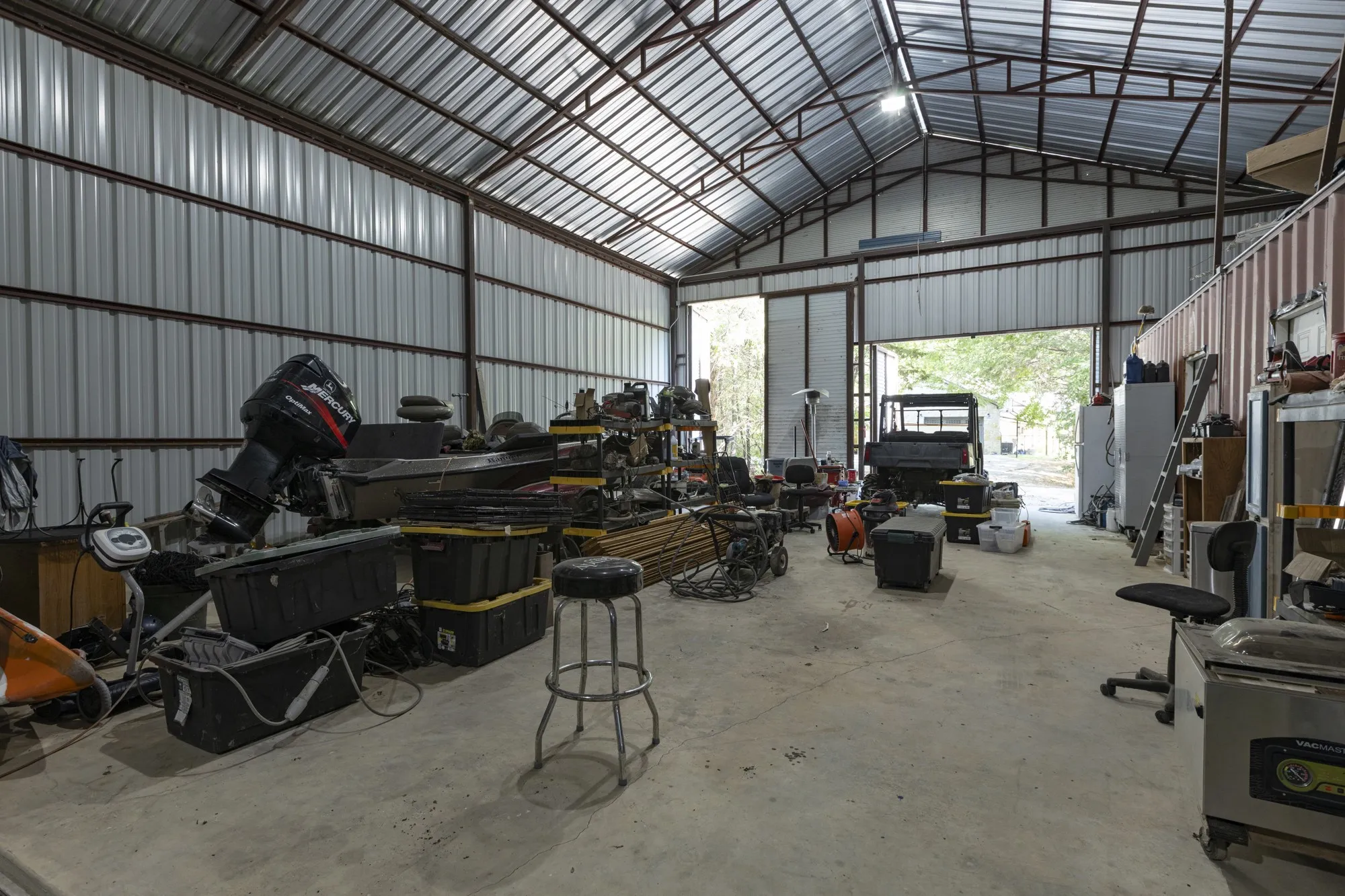 Metal-framed structure with a concrete floor, a corrugated metal roof, and an overhead door