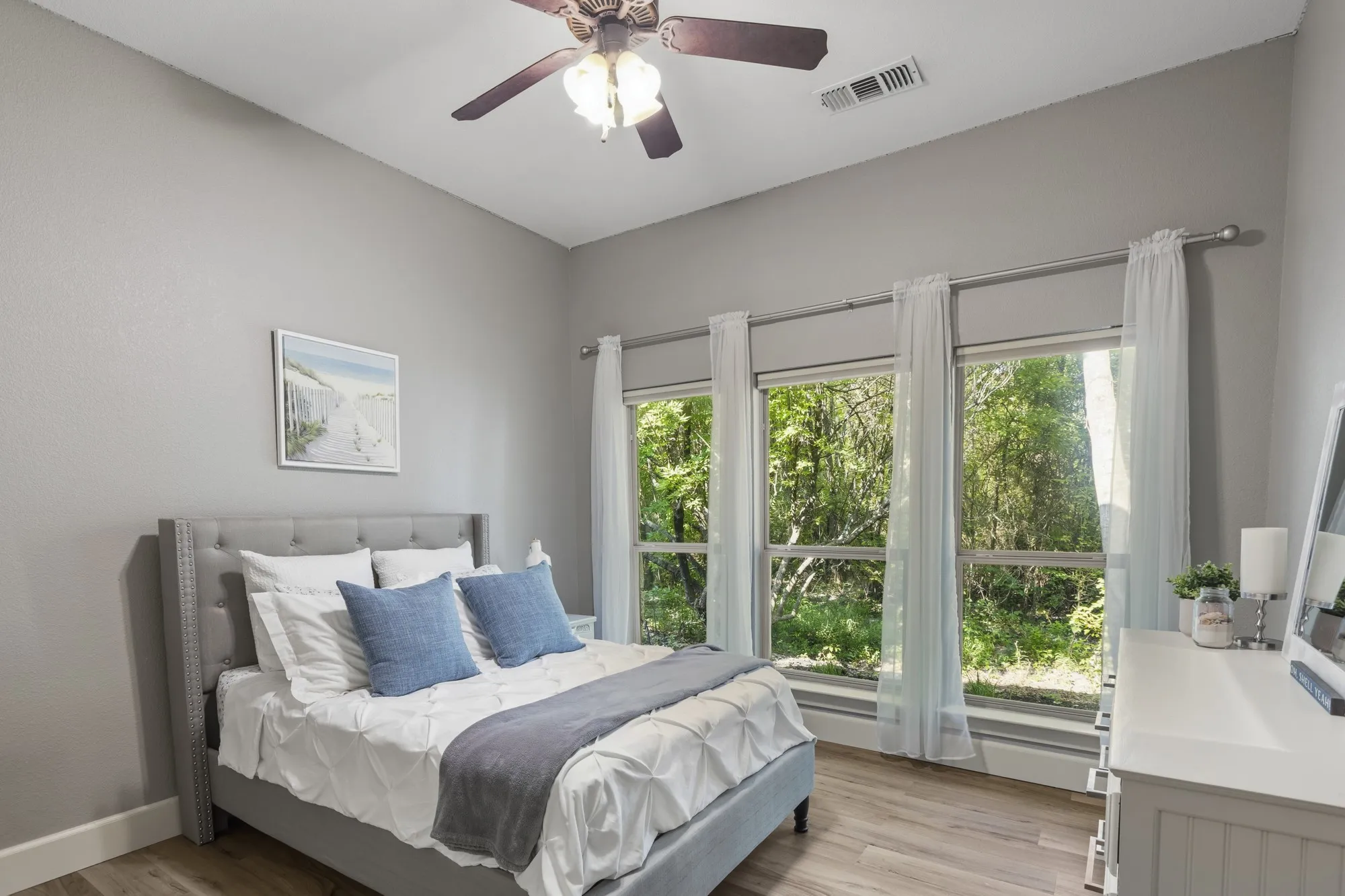 Vaulted ceiling with a ceiling fan, three pane windows, wood-finish flooring, and a large white dresser