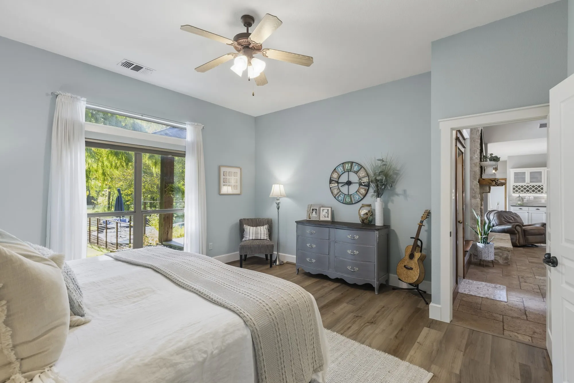Wood-finish flooring, ceiling fan, and large windows with transom detail