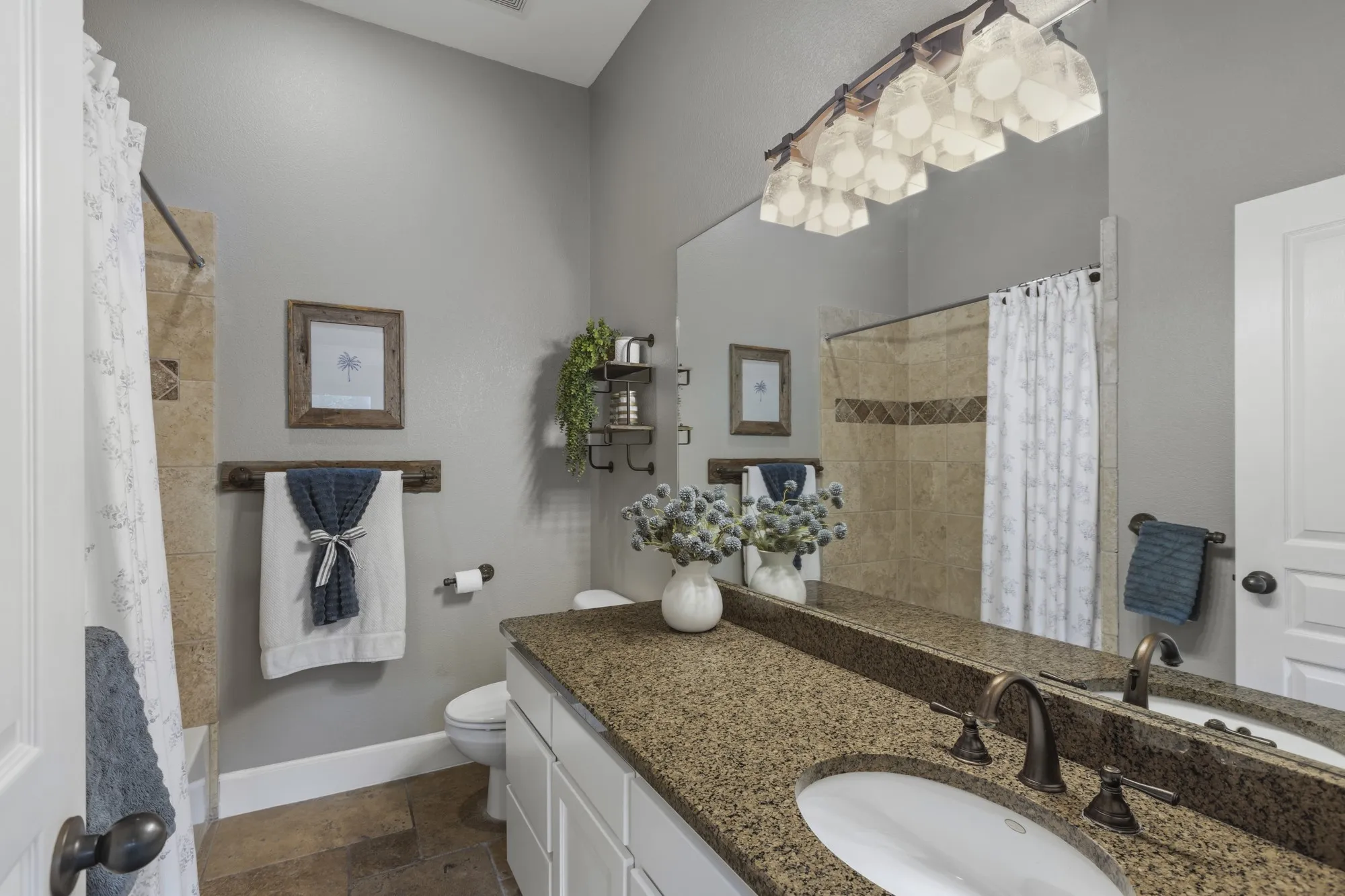 Vaulted bathroom ceiling with a tiled shower, single vanity with a solid surface countertop, and large wall-mounted mirror