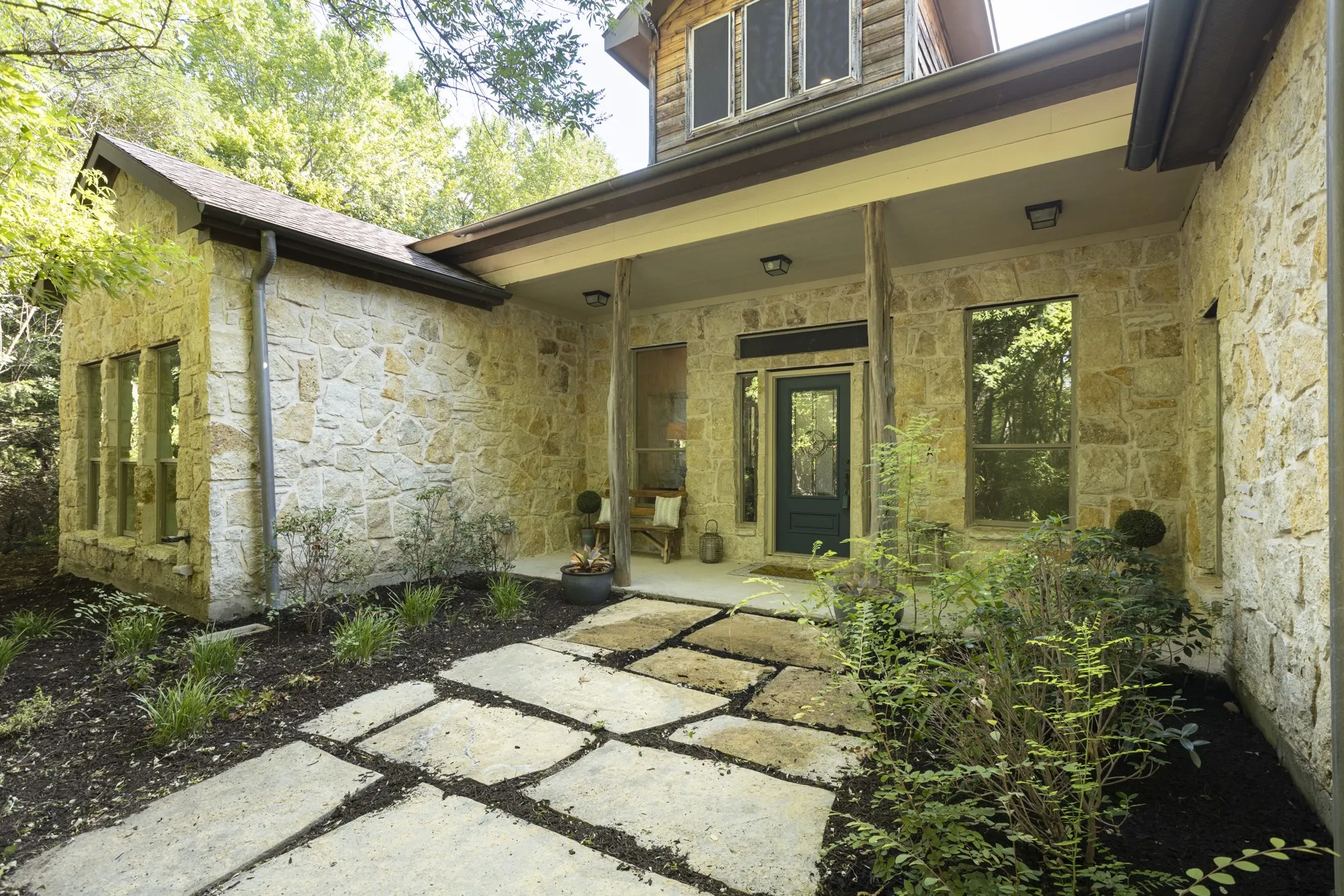 Stone exterior with a covered entry, dark paneled entry door, and multi-paned windows