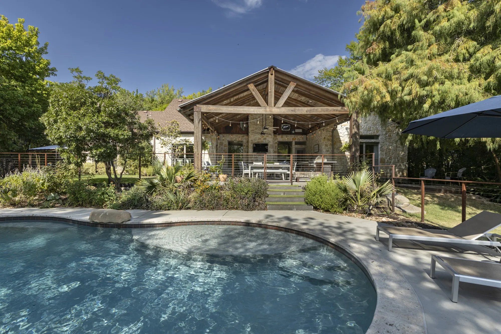 Curved-edge swimming pool with integrated spa, concrete decking, and natural stone accents