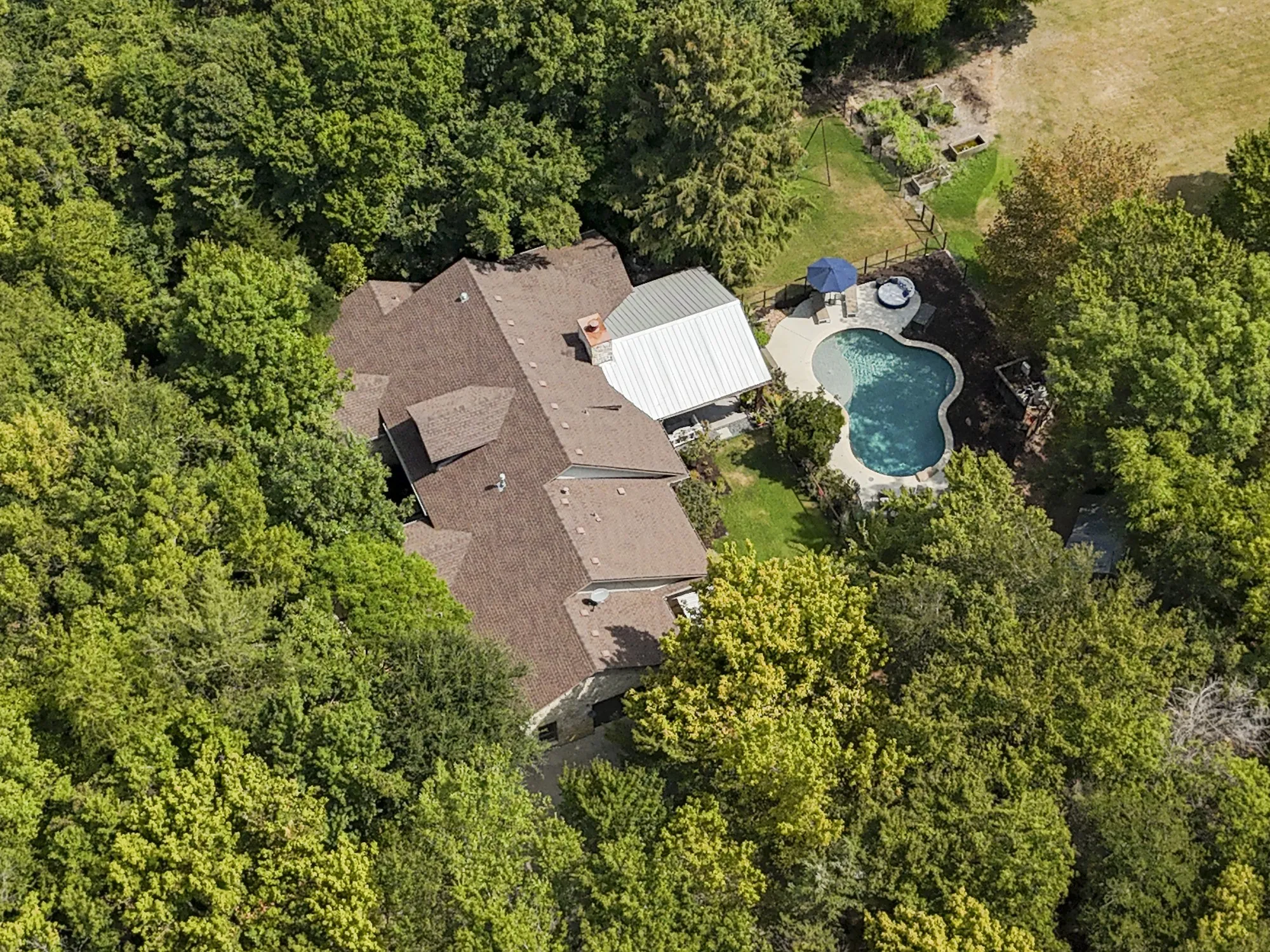 Backyard with a freeform swimming pool, adjacent spa, and a covered patio structure
