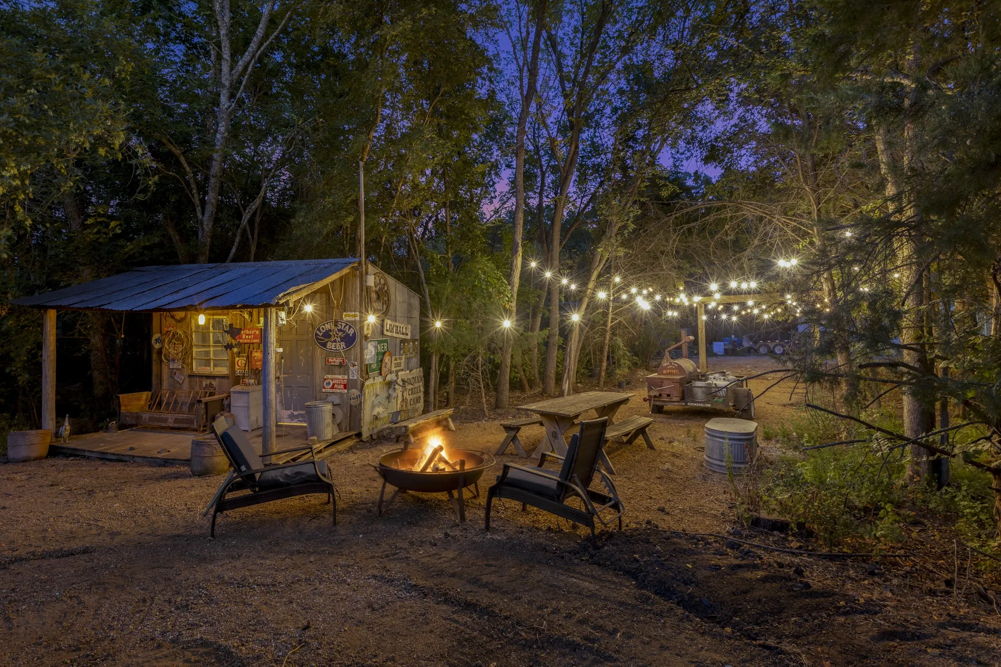 Wood-sided shed with a metal roof, outdoor string lighting, and a metal fire pit