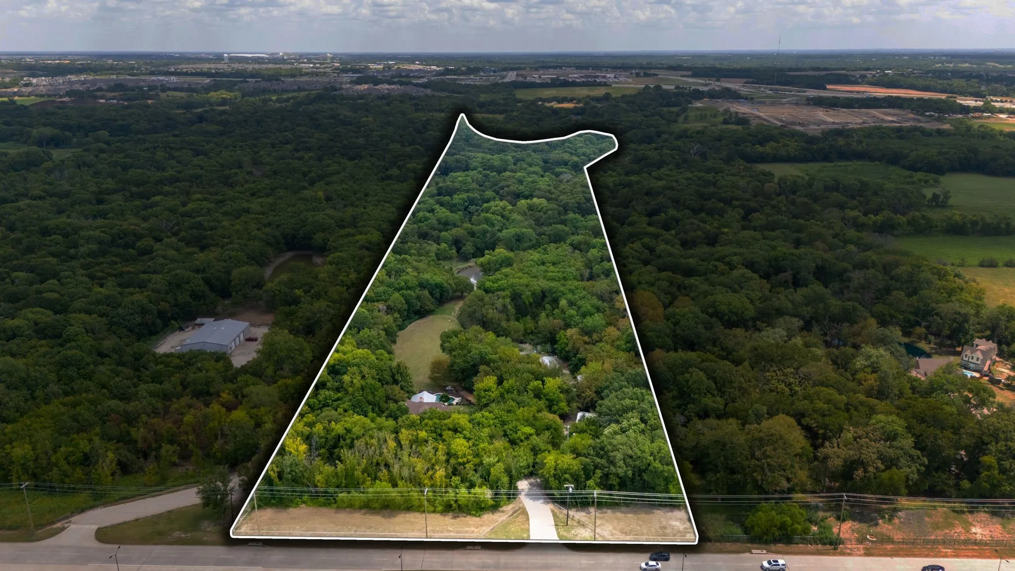 Expansive wooded acreage featuring a defined property boundary, natural creek, and a private driveway