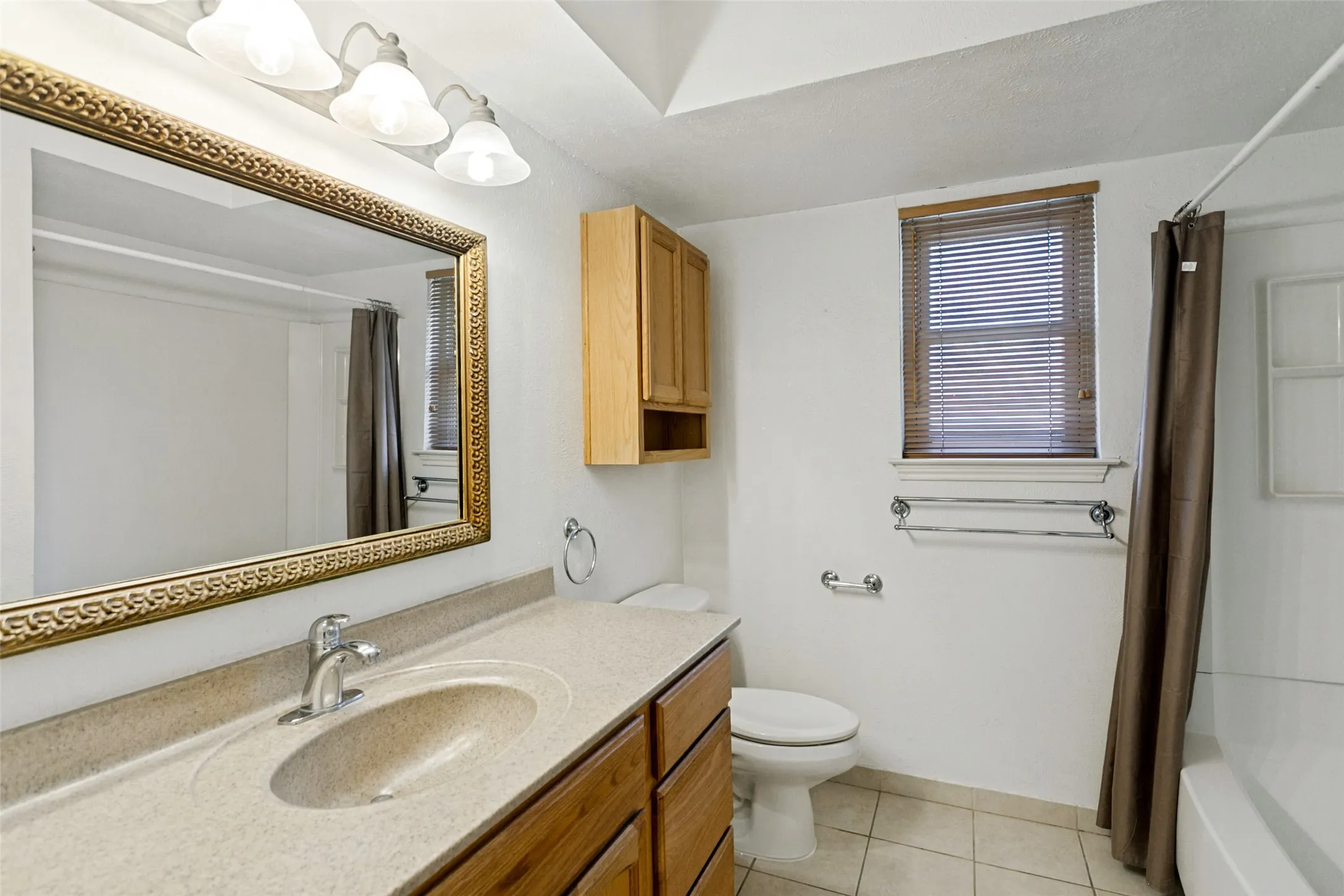 Vanity with integrated sink, wood-finish cabinetry, and a large framed mirror