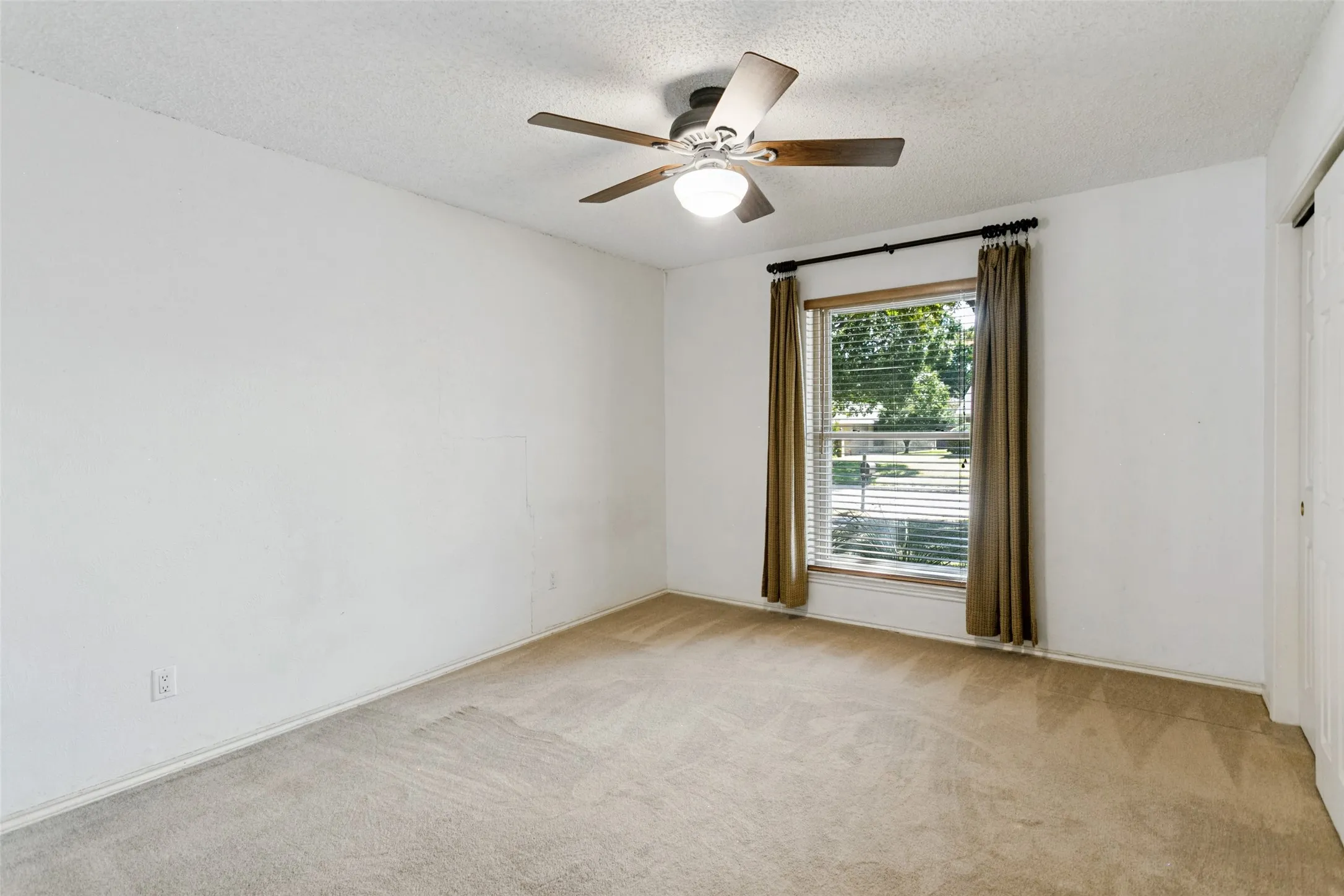 Carpeted flooring, window with blinds and drapes, ceiling fan with light fixture, and closet with sliding doors