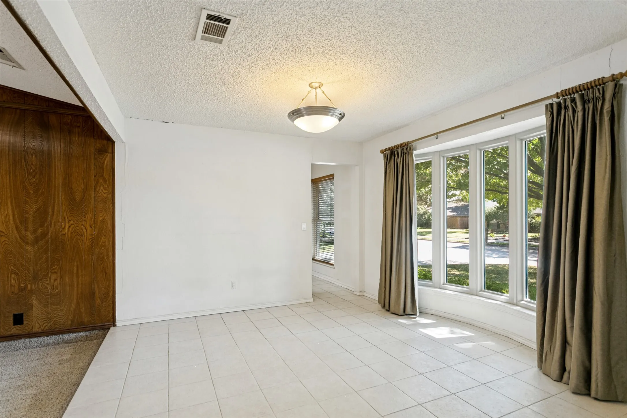 White tile flooring, wood-paneled wall, overhead light fixture, and multiple windows