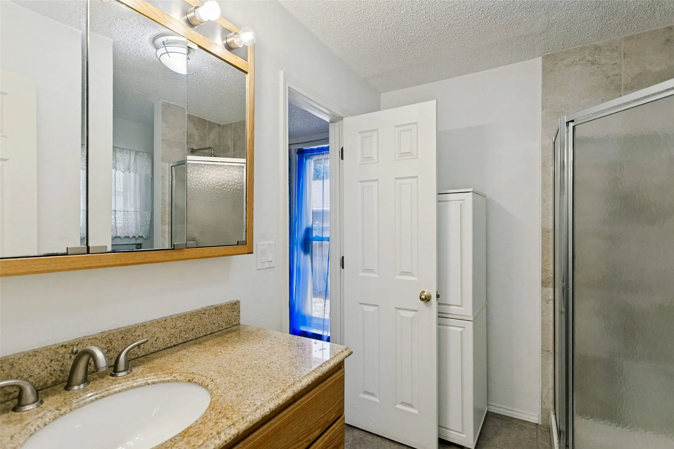 Vanity with an oval basin, dual-handle faucet, and granite-style countertop
