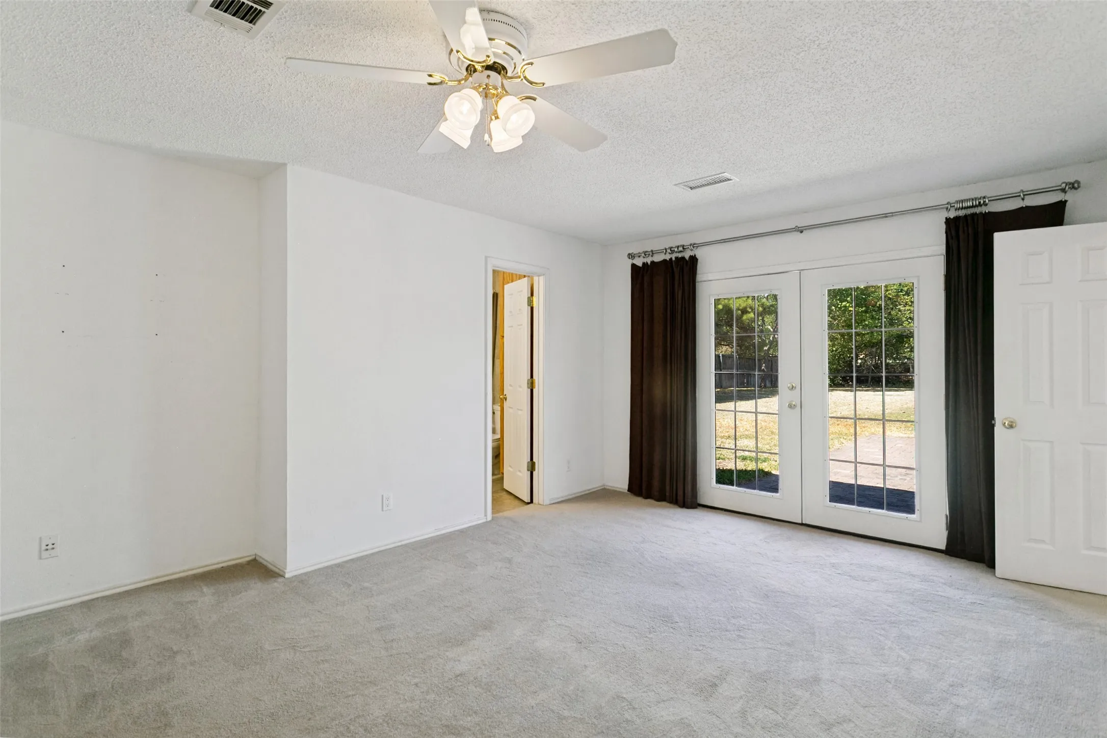 Wall-to-wall carpeting, white walls, and a ceiling fan with light