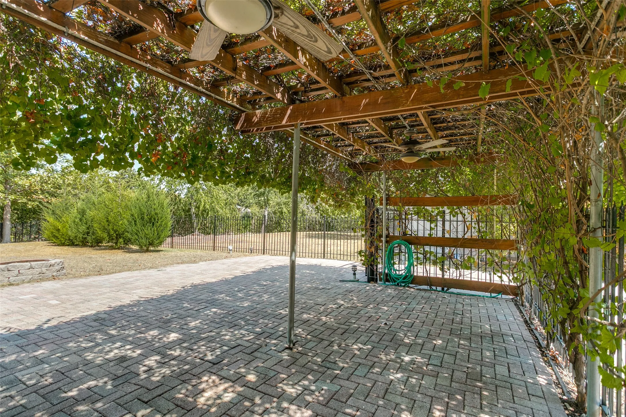 Patio featuring a wood pergola with integrated ceiling fans, brick paver flooring, and perimeter fencing