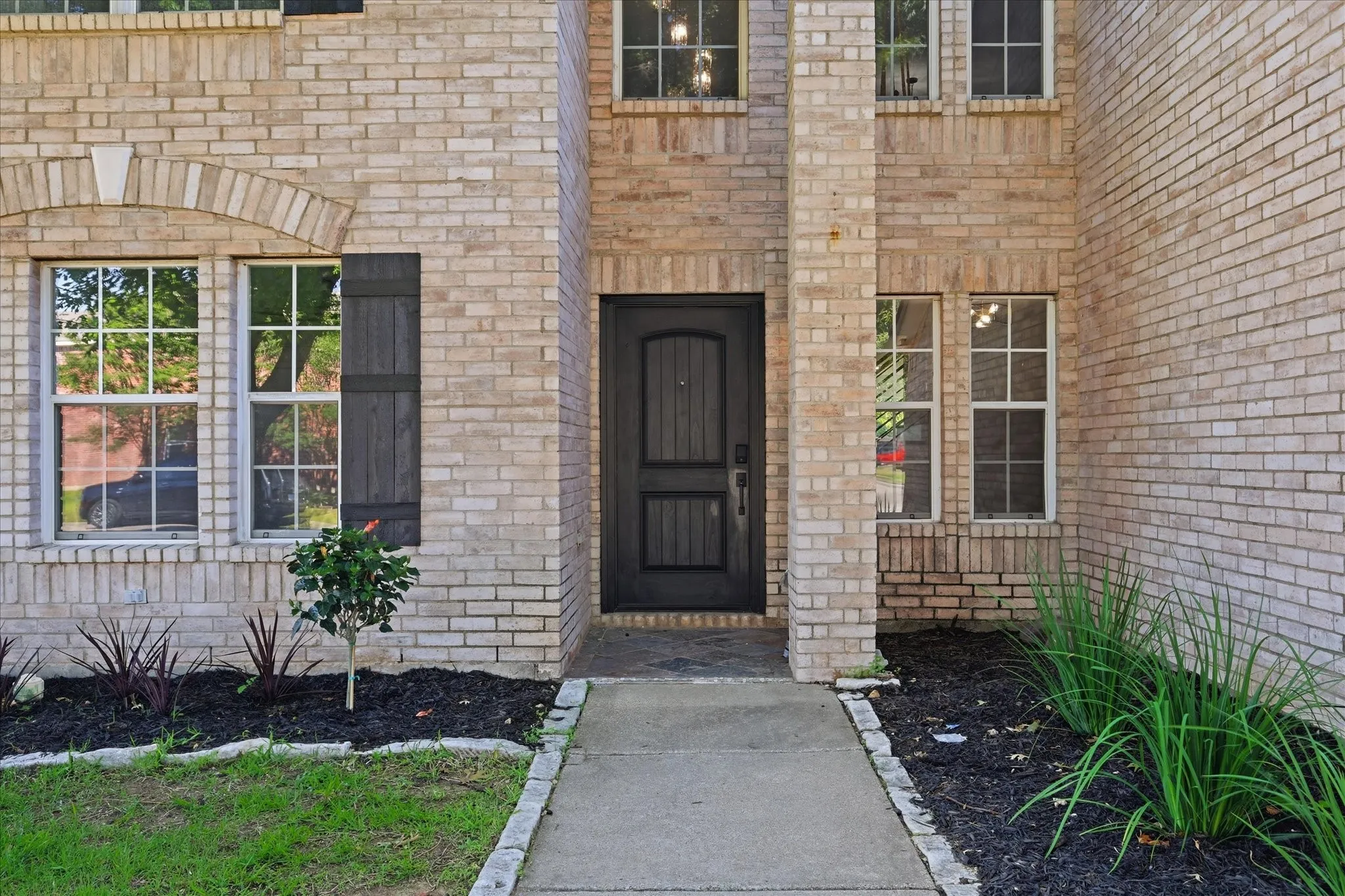 Light-colored brick exterior with a dark-paneled entry door