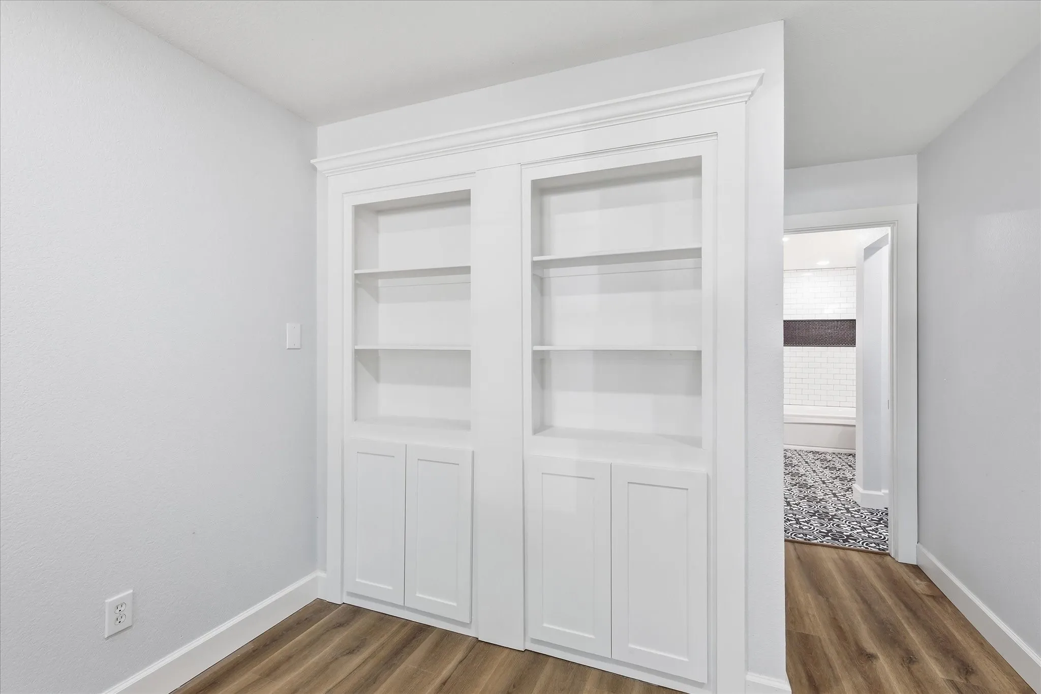Built-in white shelving and cabinetry, wood-finish flooring, and white trim throughout