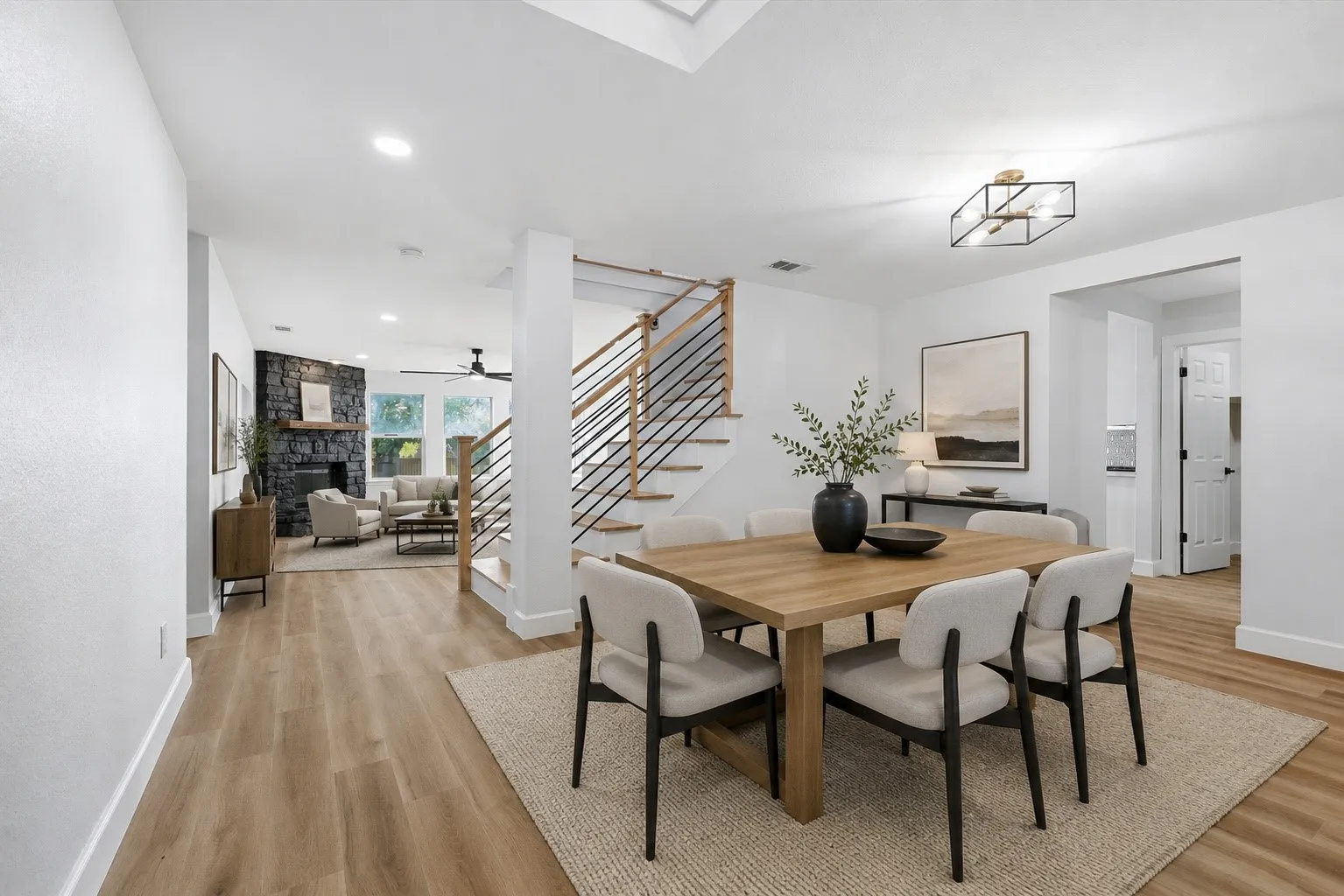 Contemporary open-concept interior with wood-finish flooring, recessed lighting, and a modern staircase featuring horizontal metal railings
