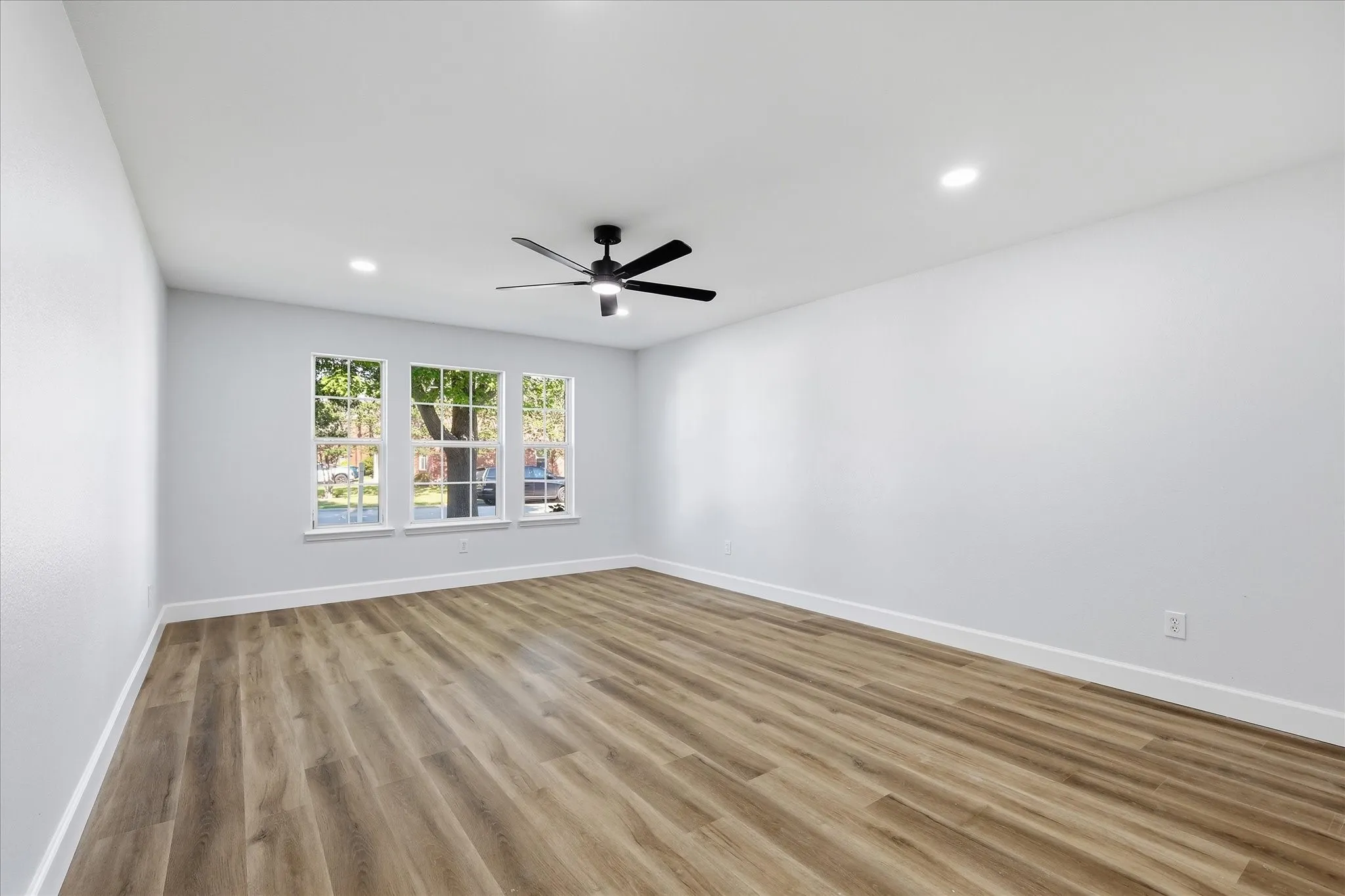 Wood-finish flooring, recessed lighting, ceiling fan, and multiple windows