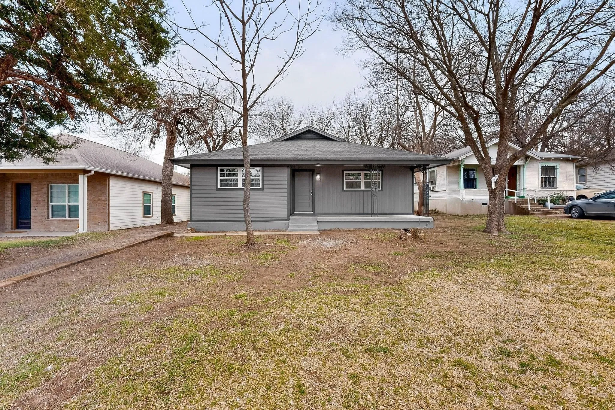 Single-story residence featuring a gray exterior, white-framed windows, and an asphalt shingle roof