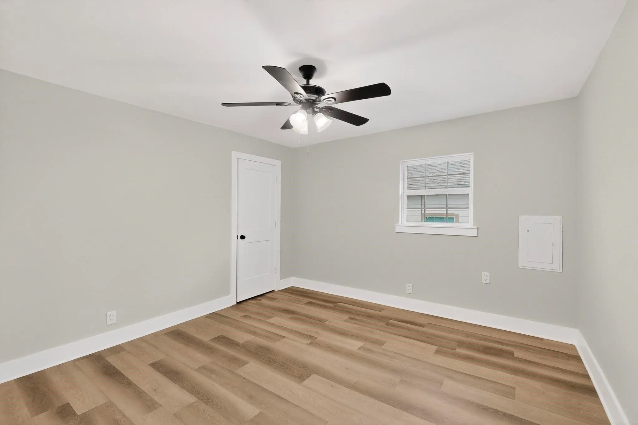 Neutral wall paint, wood-finish flooring, white trim, a ceiling fan with light, and a single window