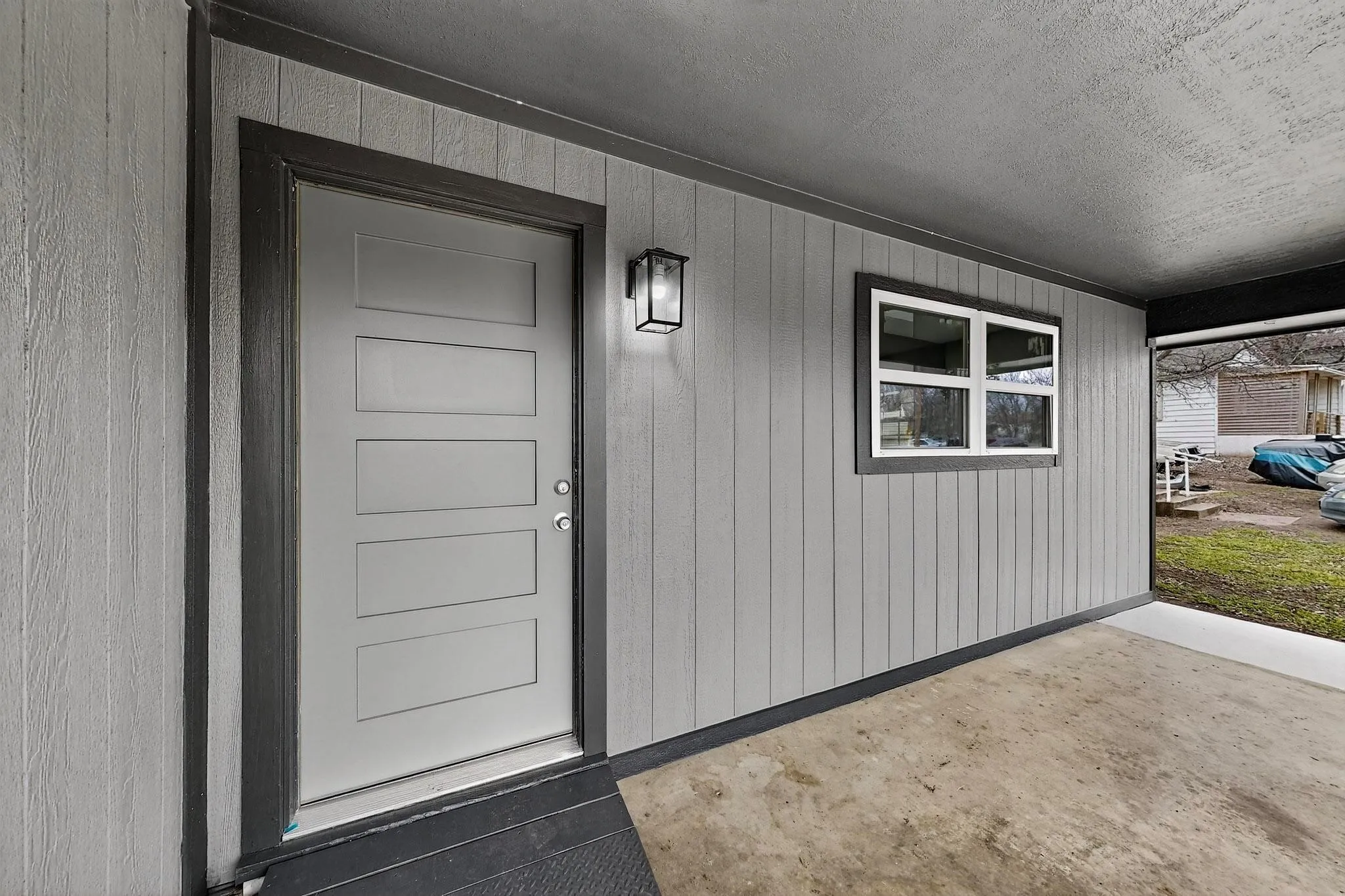 Covered entrance with vertical panel siding, modern exterior lighting, and a contemporary entry door