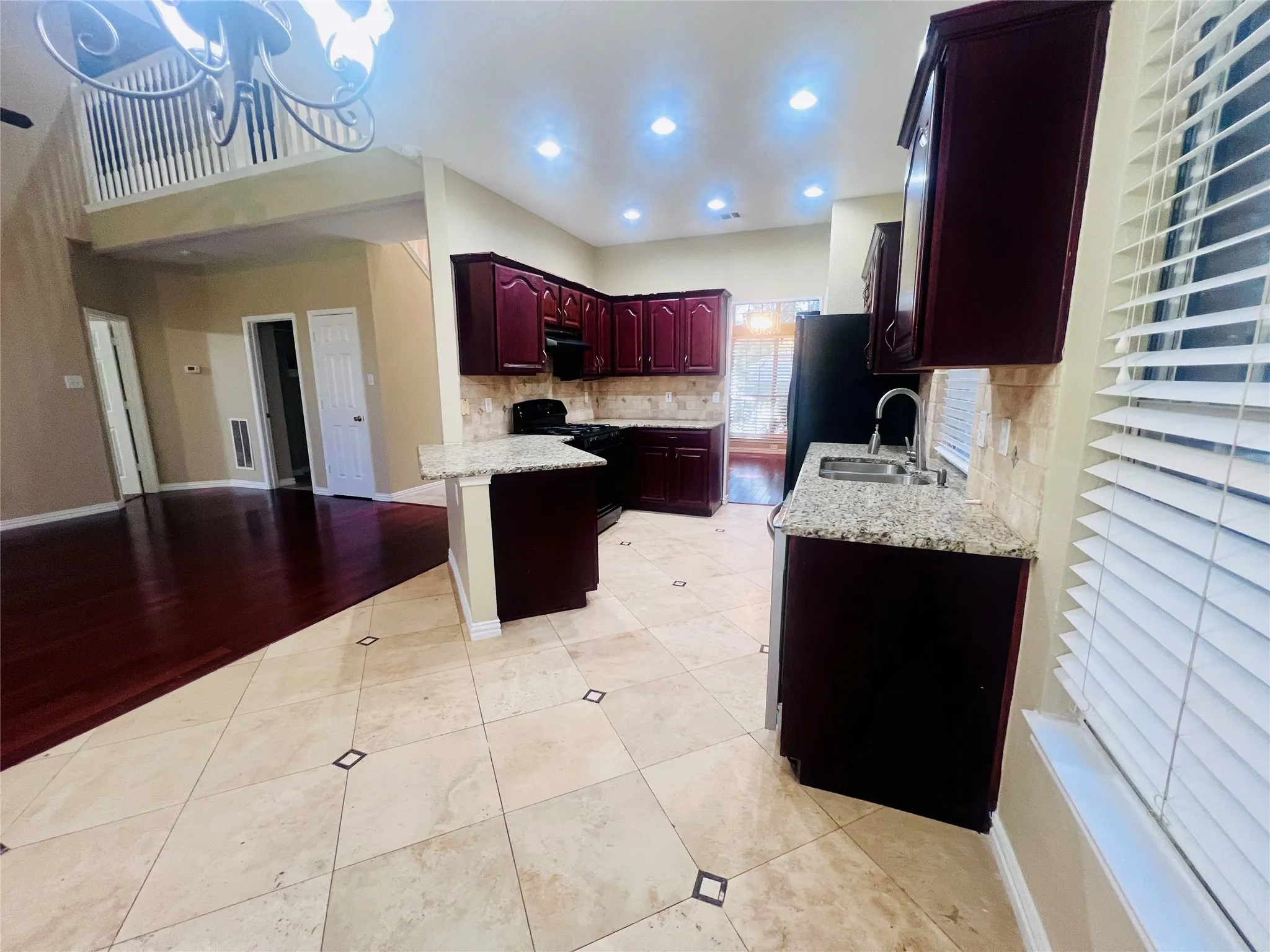 Kitchen featuring dark brown cabinets, black gas range oven, a chandelier, light stone counters, and recessed lighting
