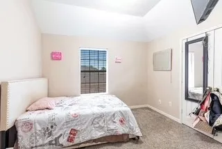 Bedroom with vaulted ceiling and carpet floors