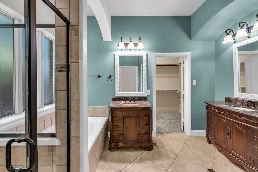 Dual vanity with ornate wood cabinetry, integrated sinks, and matching framed mirrors