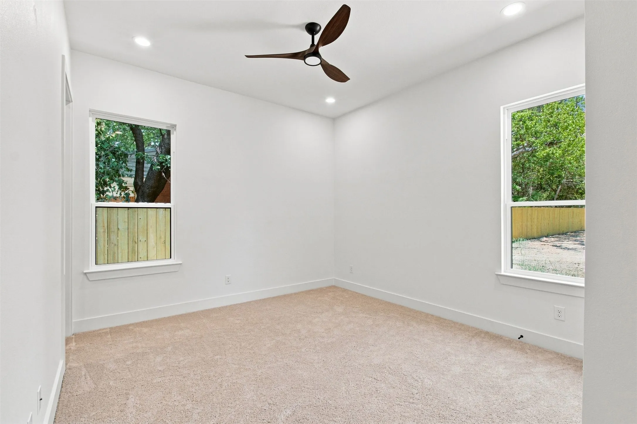 Recessed lighting, wood-finish ceiling fan, two windows, wall-to-wall carpeting, and white trim