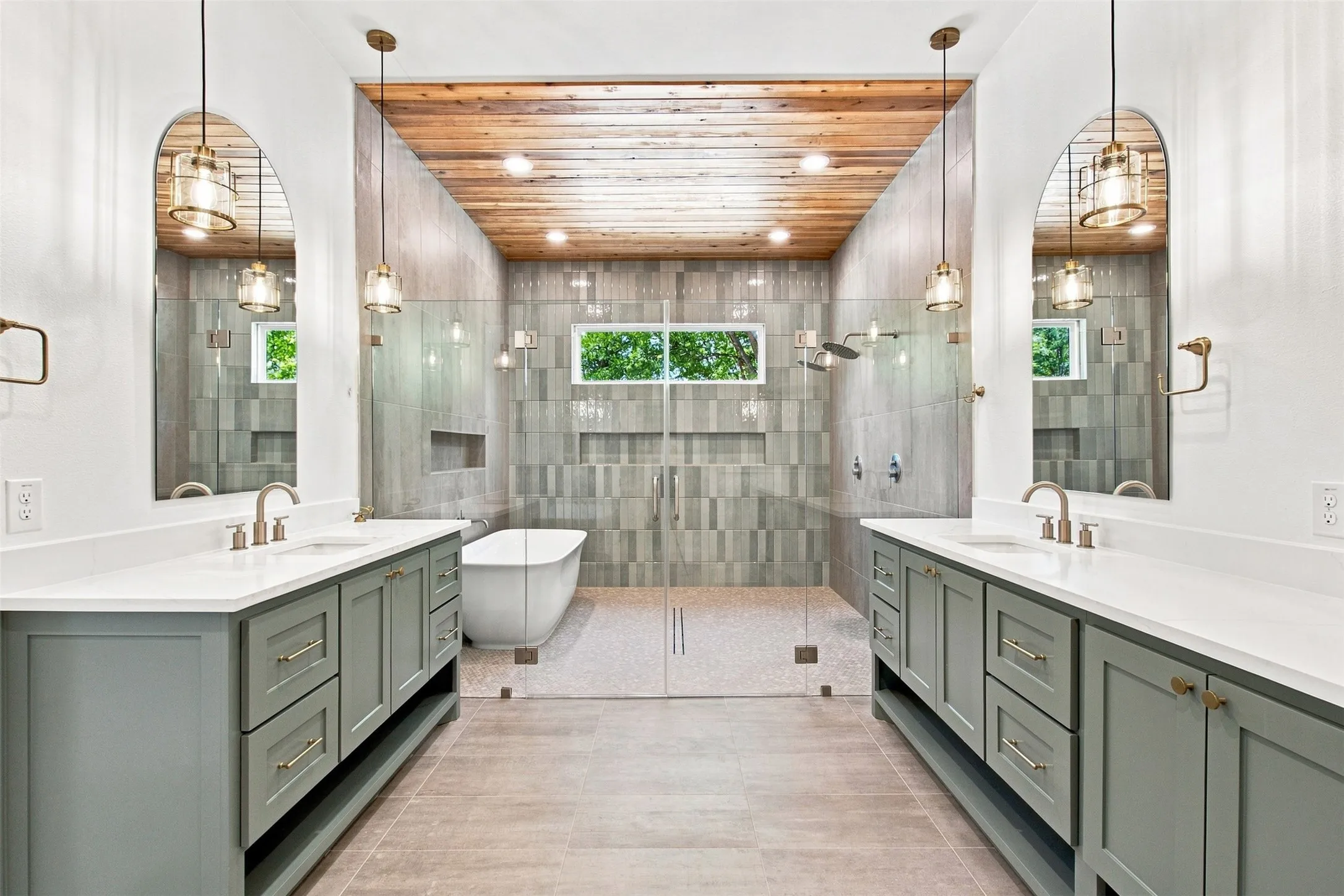Dual vanities with white countertops, a freestanding soaking tub, a walk-in shower with glass enclosure, a wood-paneled ceiling, and pendant lighting fixtures