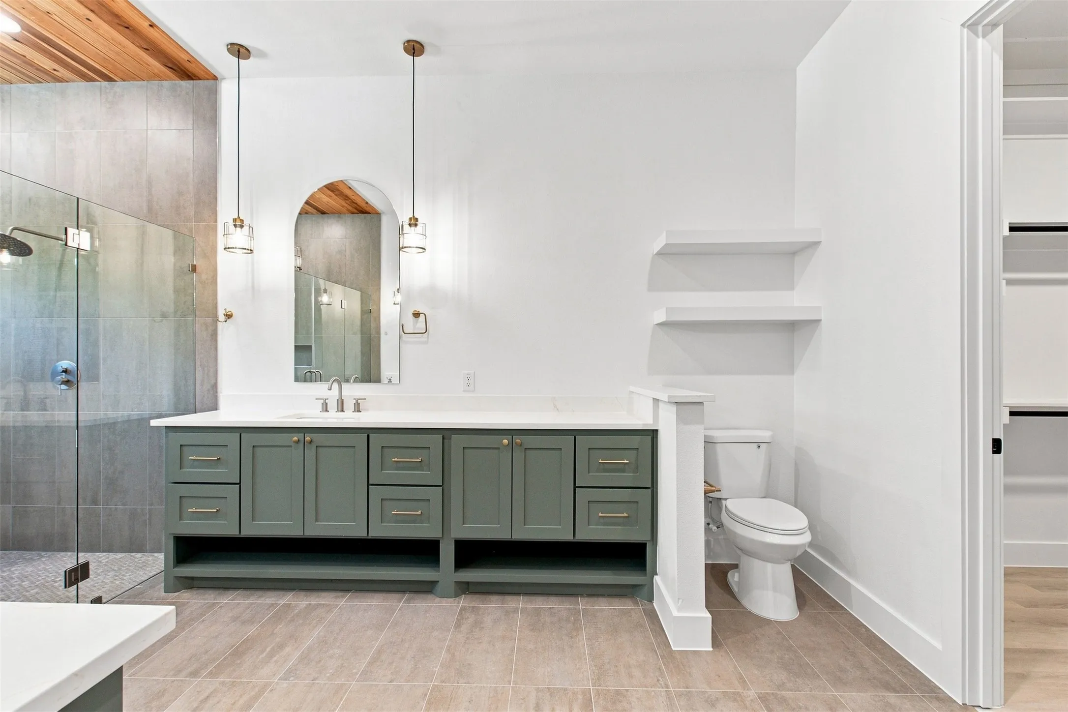 Spacious bathroom featuring a double vanity with green cabinetry, a glass-enclosed shower, a wood-finish ceiling accent, and built-in shelving