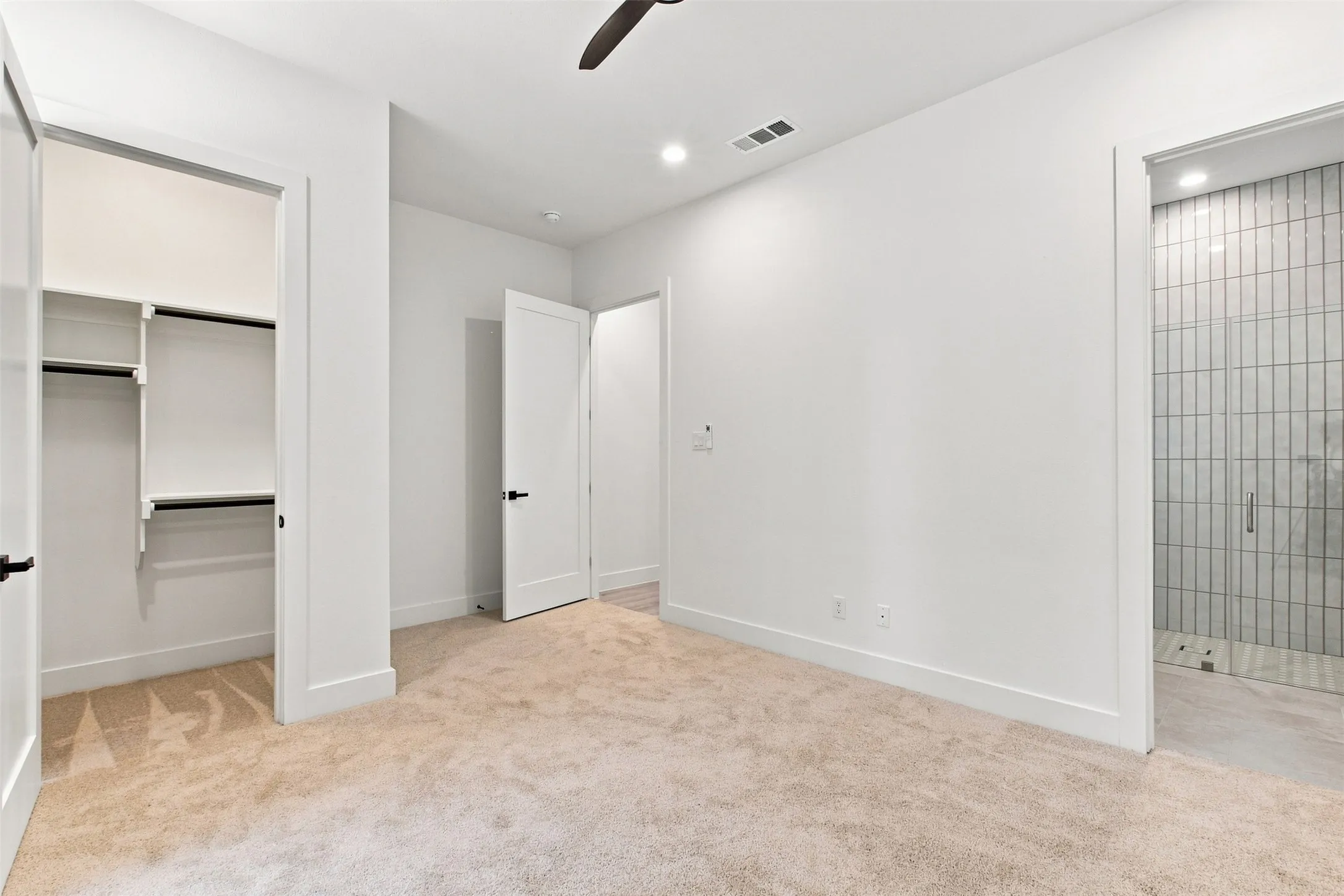 Recessed lighting, ceiling fan, built-in closet shelving, and a shower with vertical tile