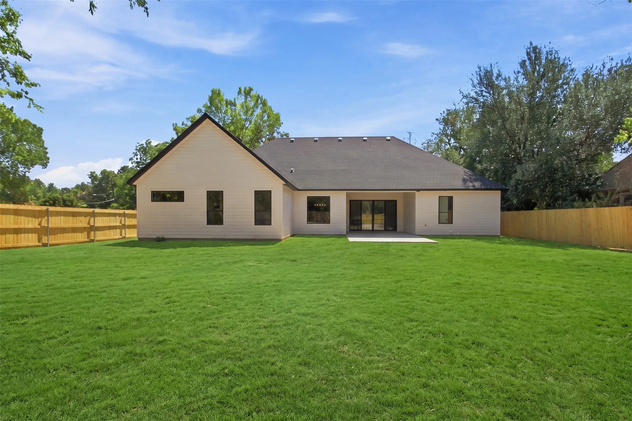 Expansive green lawn with a newly installed wood fence