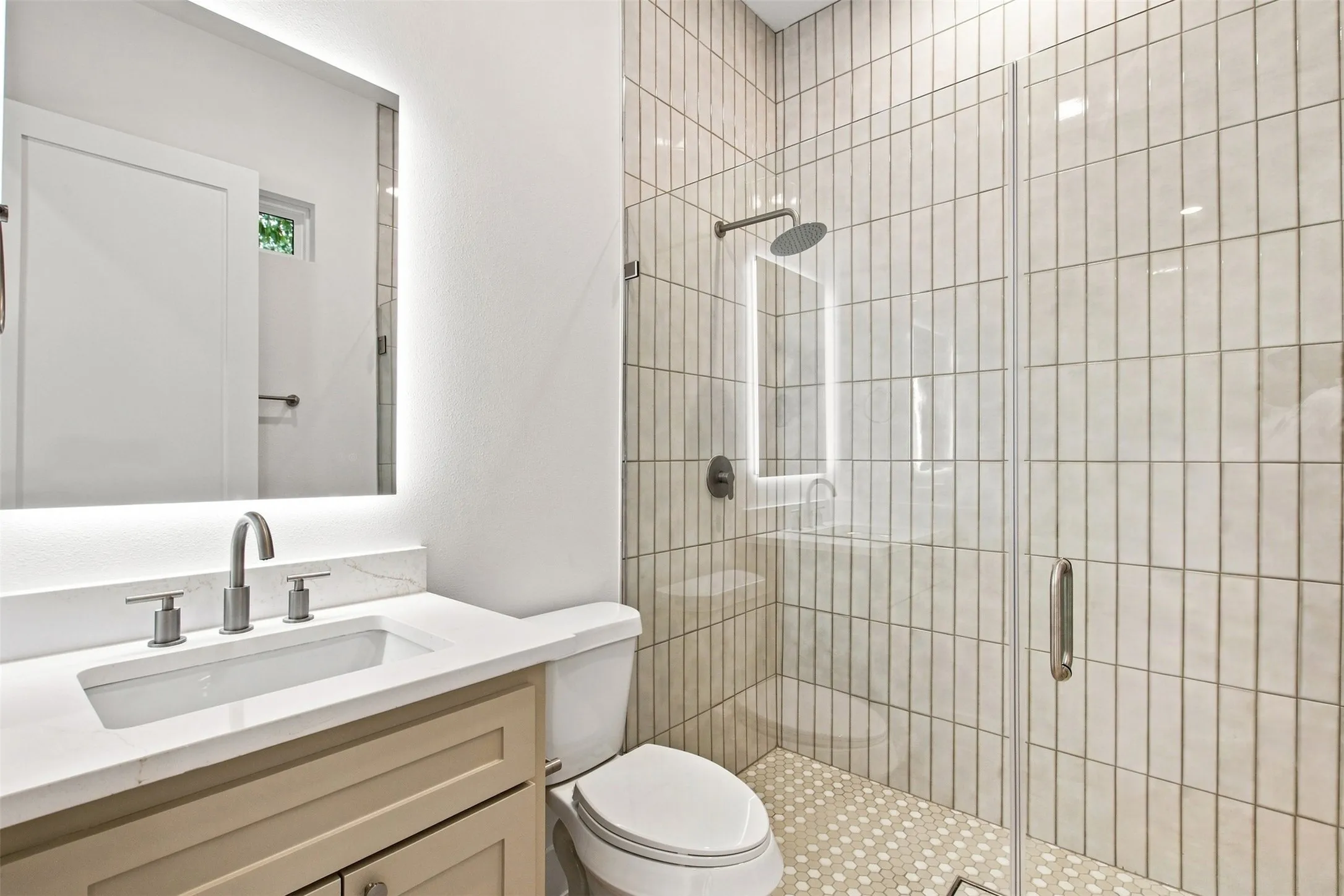 Vanity with an integrated sink, illuminated mirror, and brushed nickel fixtures