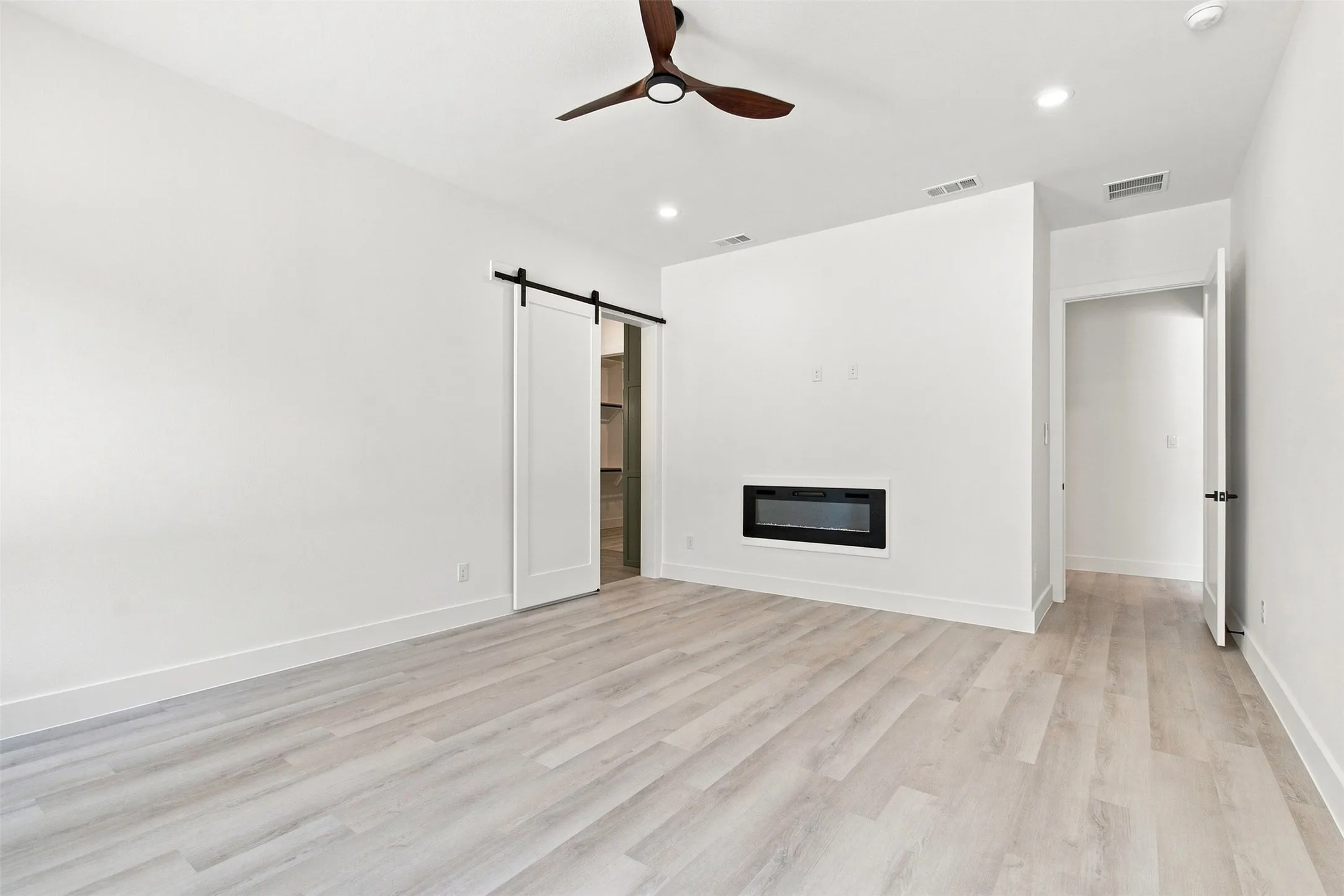 Recessed lighting, wood-finish flooring, ceiling fan, built-in fireplace, and barn door