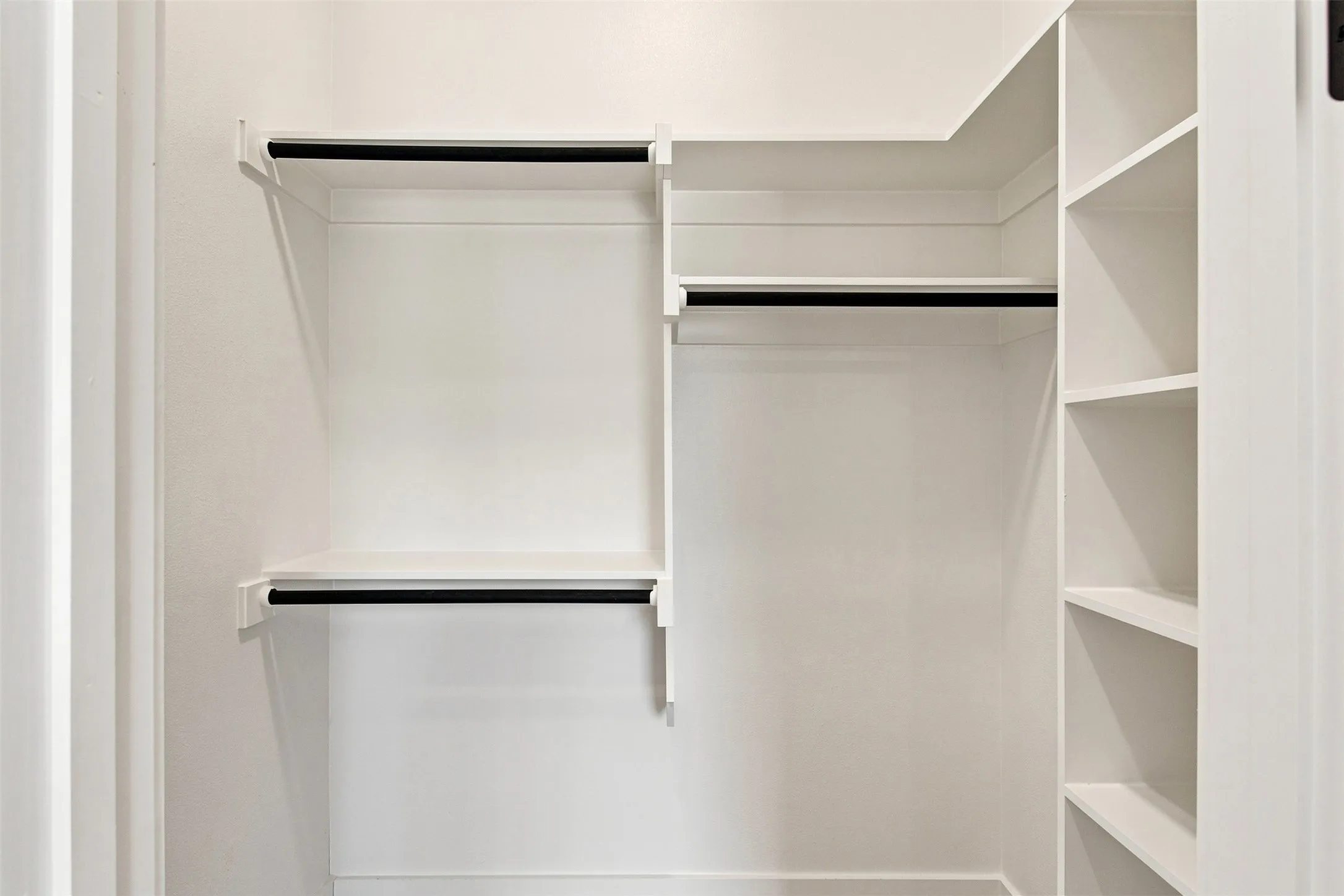 White-painted closet system featuring multiple hanging rods and integrated shelving