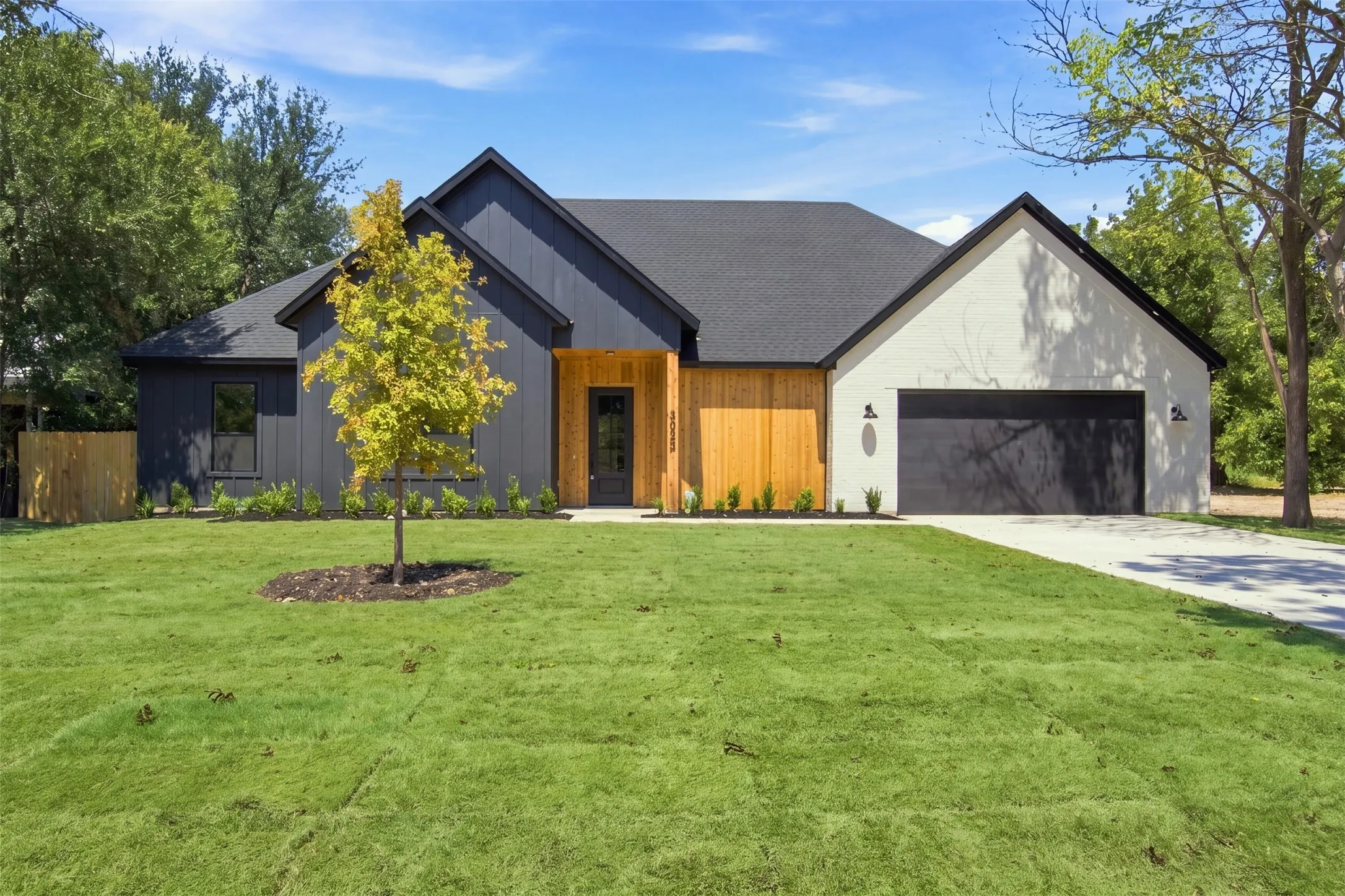 Modern exterior featuring dark vertical siding, light-toned brick, and natural wood accents