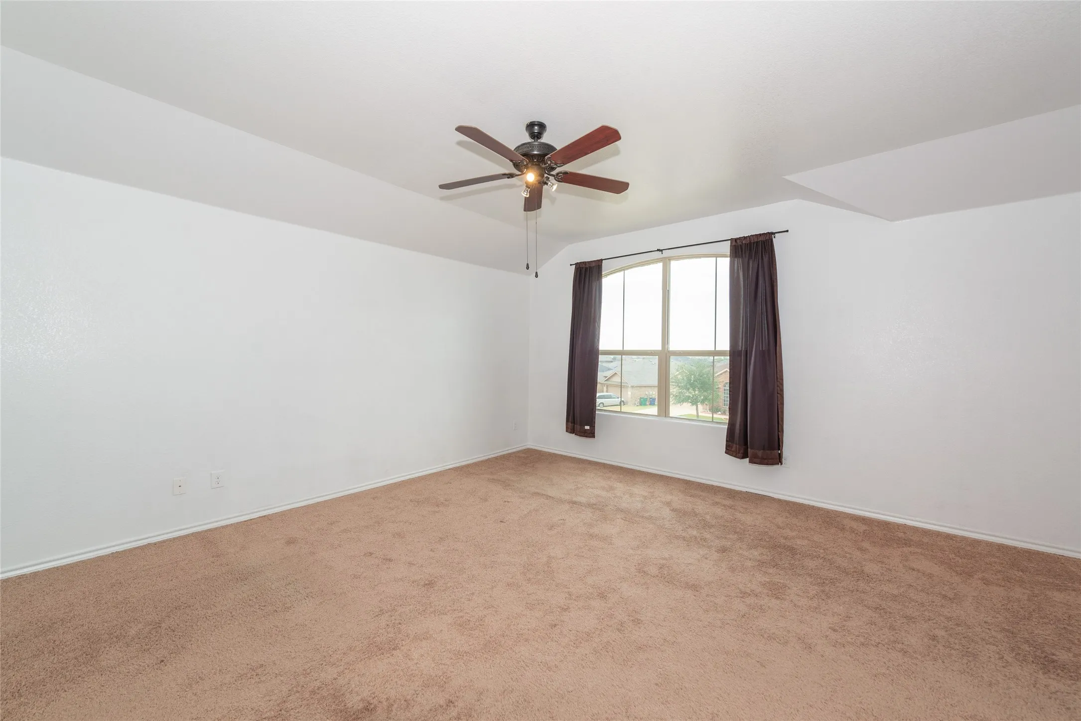 Spacious room with vaulted ceilings and neutral carpeting
