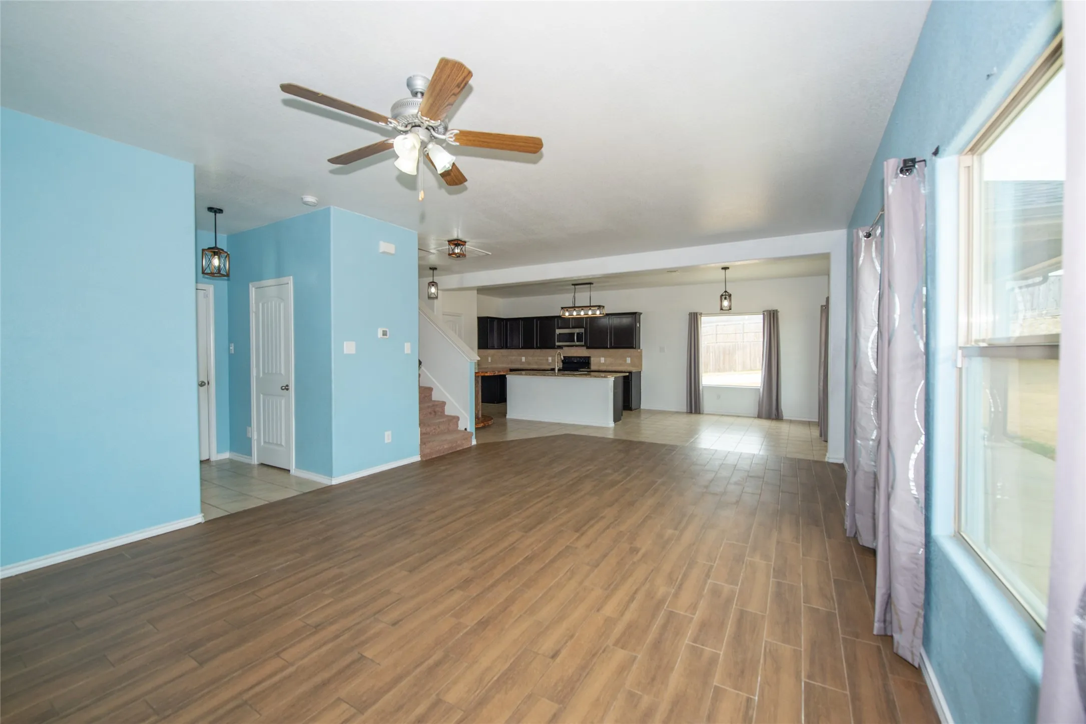 Spacious open-concept living area featuring wood-finish flooring, ceiling fan, and recessed lighting