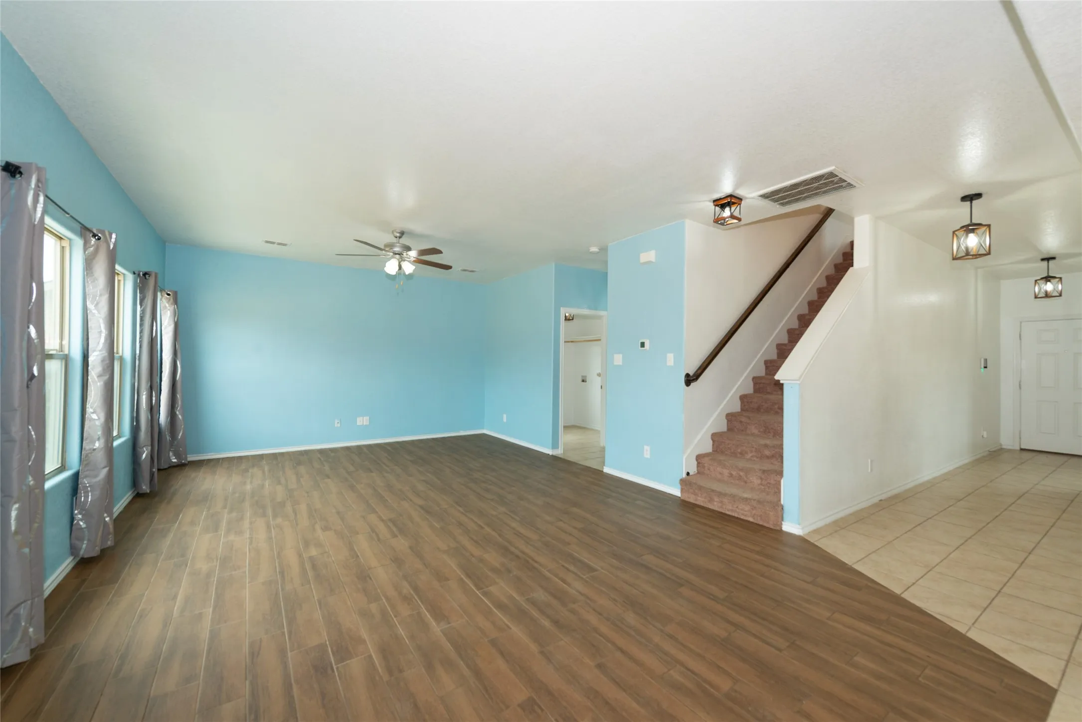 Expansive living area with wood-finish flooring and multiple windows