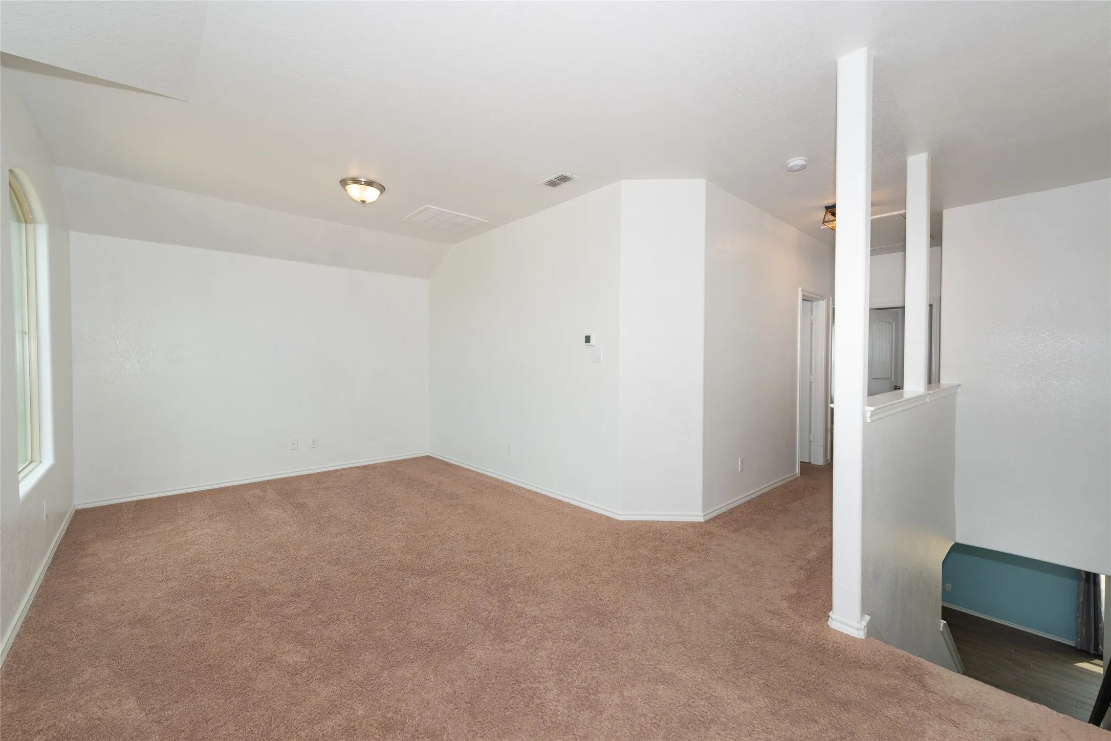 Carpeted living area with abundant natural light, recessed lighting, and a white interior color palette