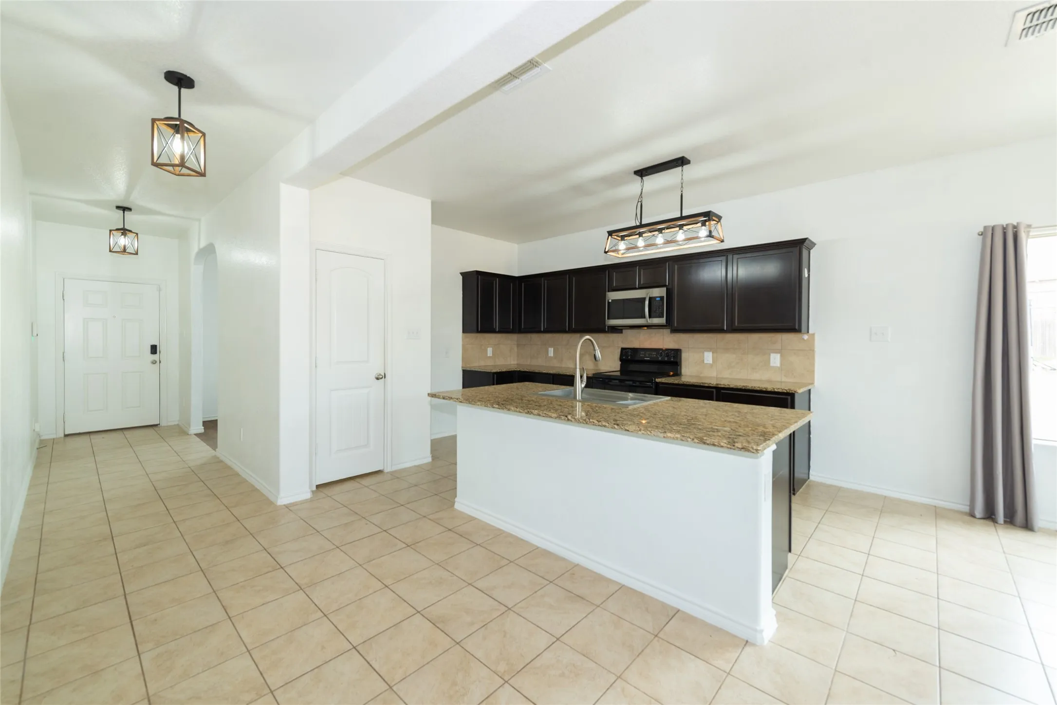 Kitchen featuring dark wood-finish cabinetry, light-toned countertops, and stainless steel appliances