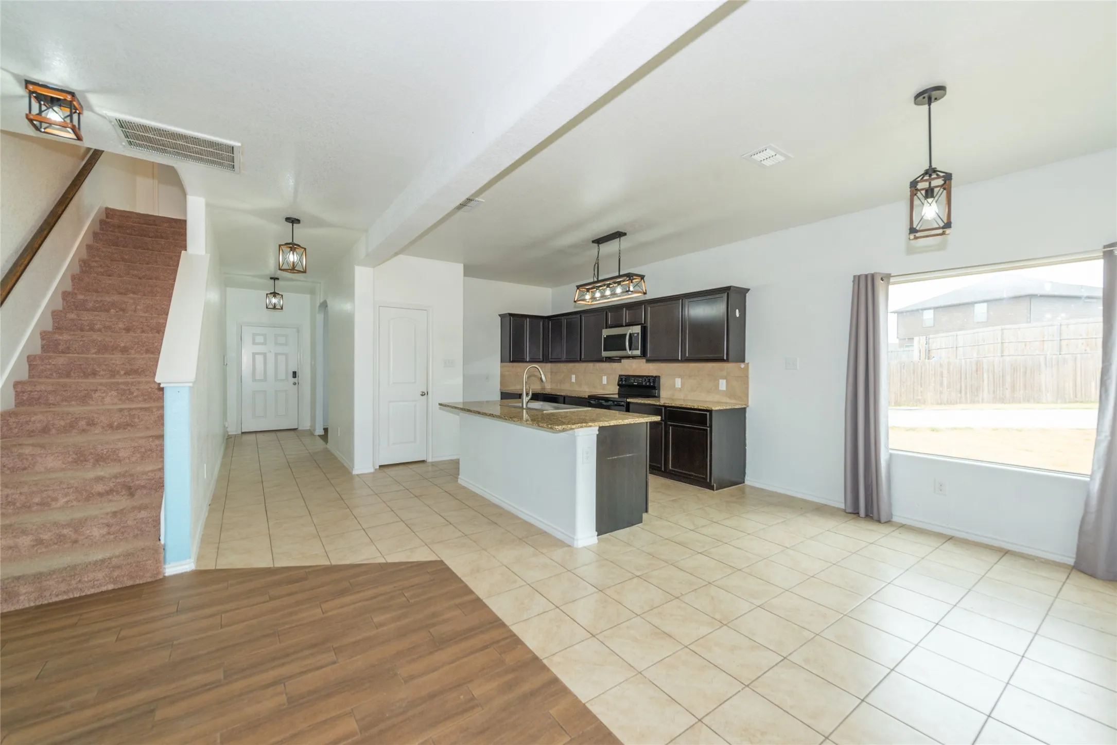 Open-concept kitchen with dark wood-finish cabinetry, a central island, and stainless-steel appliances