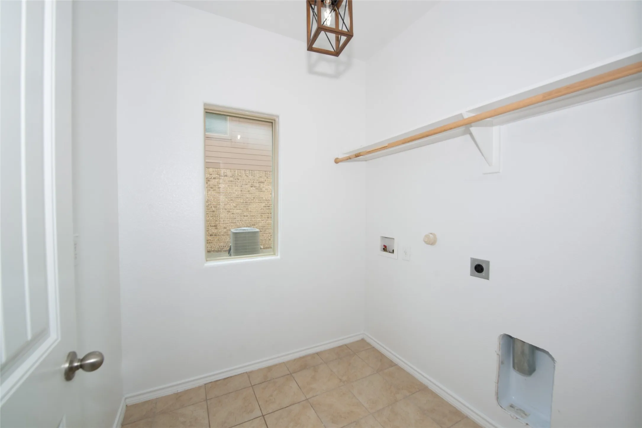 Neutral tile flooring, built-in shelving, and a wall-mounted light fixture