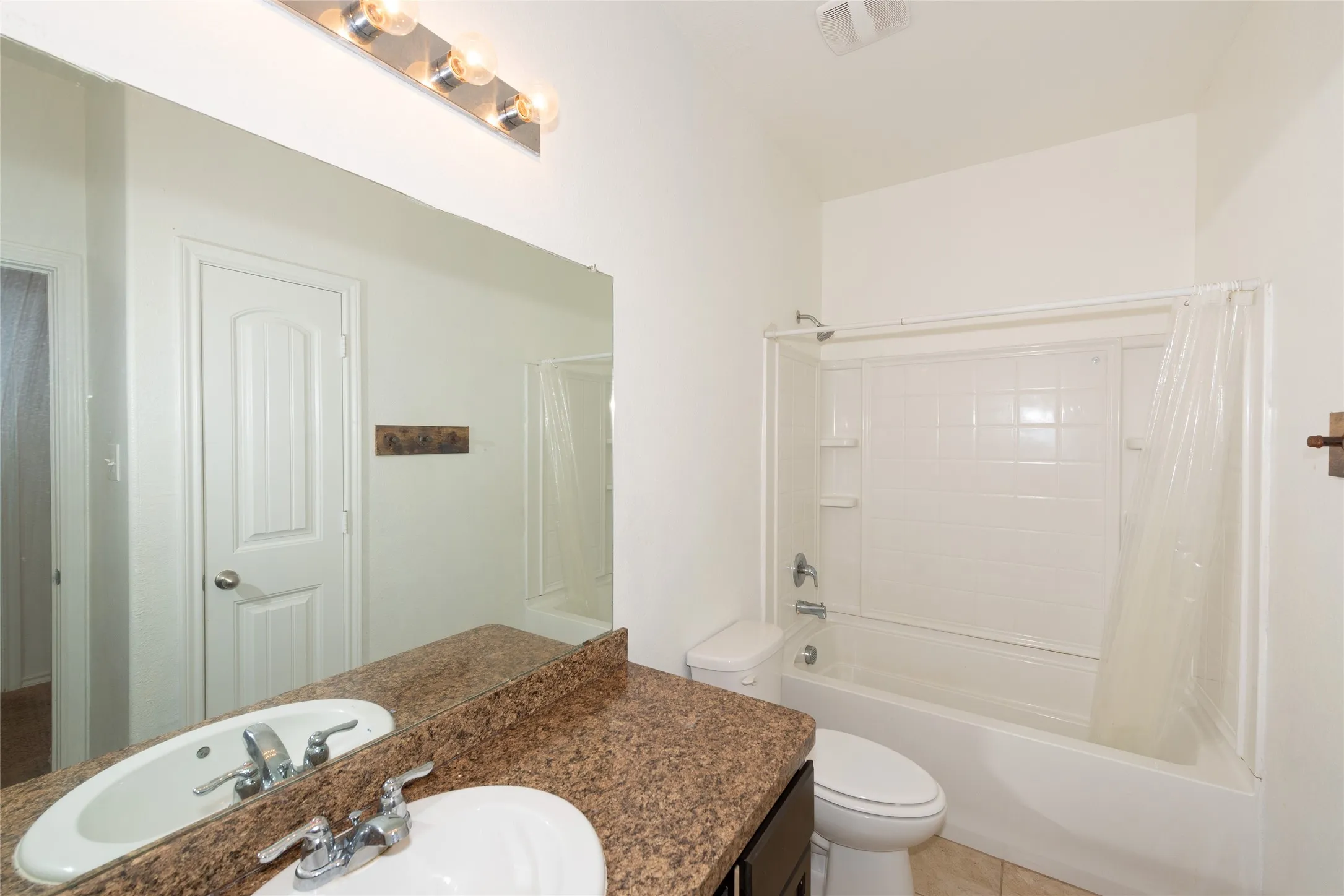 Vanity with a granite-style countertop, undermount sink, and chrome faucet