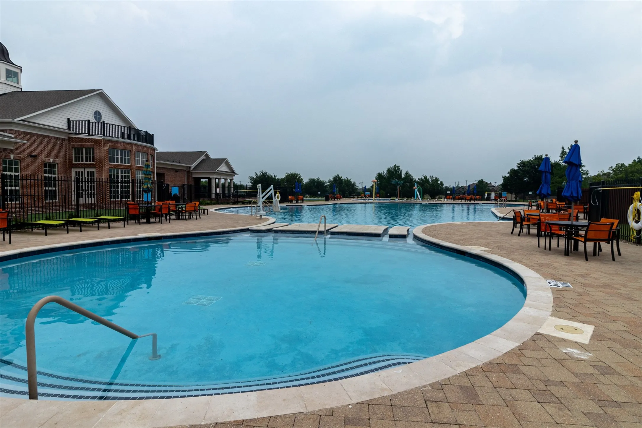 Expansive outdoor pool with integrated steps, surrounded by a paver deck
