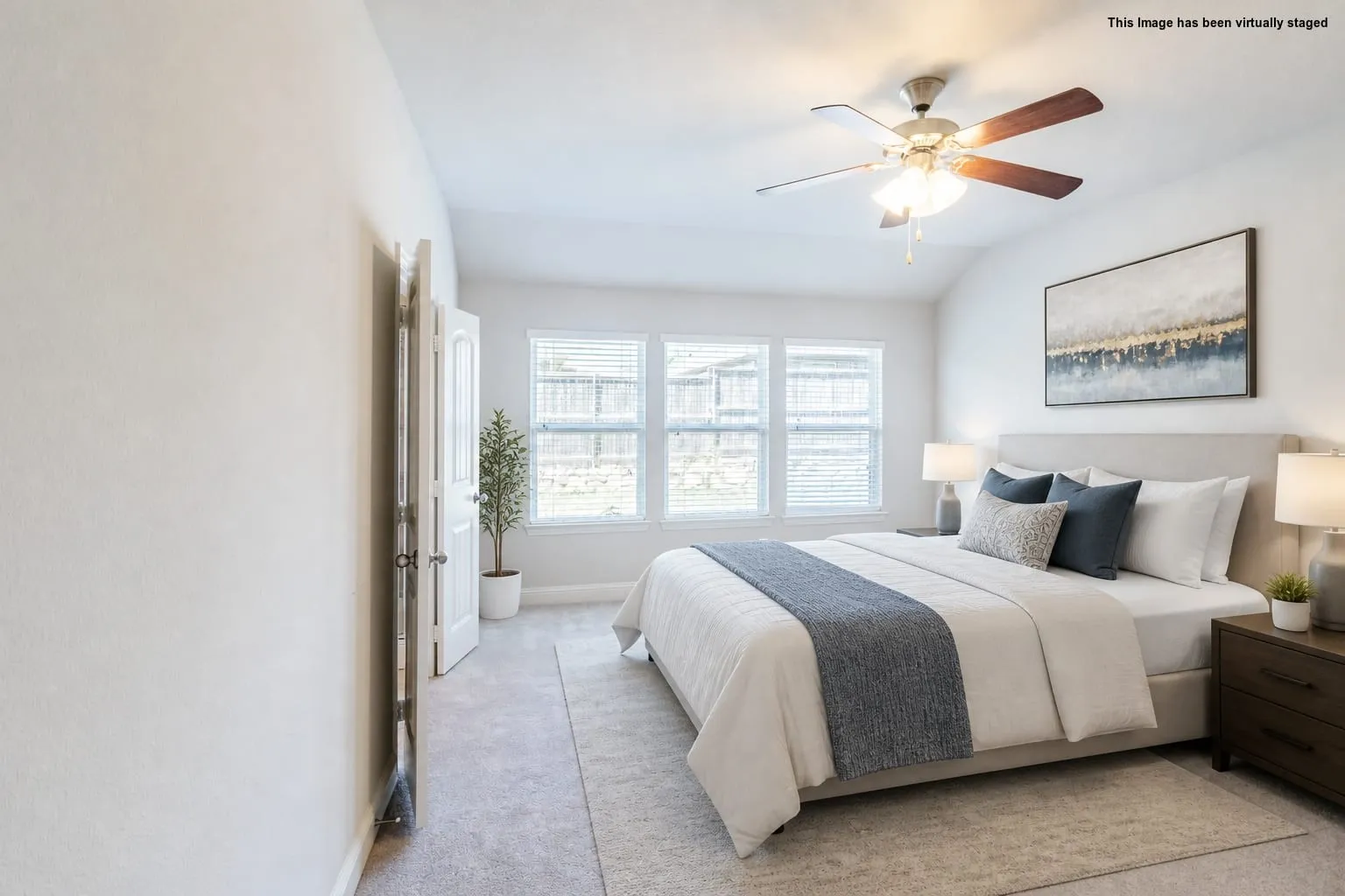 Virtual staged=>Vaulted ceiling with a ceiling fan, light-colored carpeting, and a series of three windows
