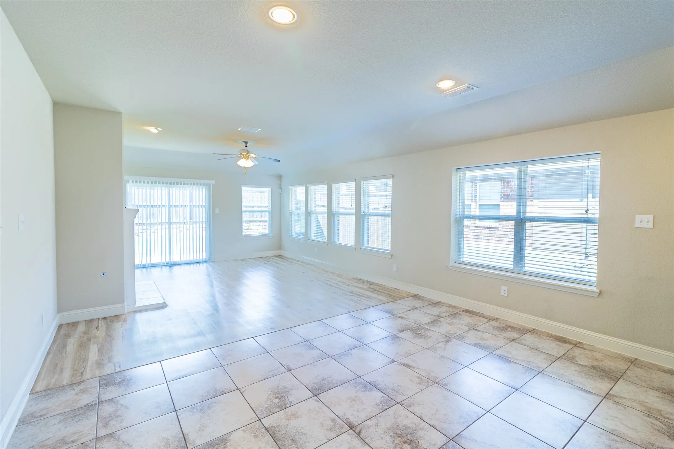 Recessed lighting, ceiling fan, sliding glass door, multiple windows, and mixed flooring