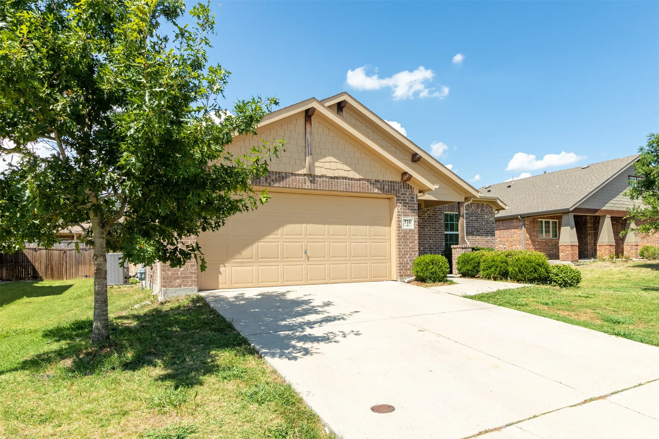 Brick and siding exterior featuring an attached two-car garage, concrete driveway, and mature landscaping