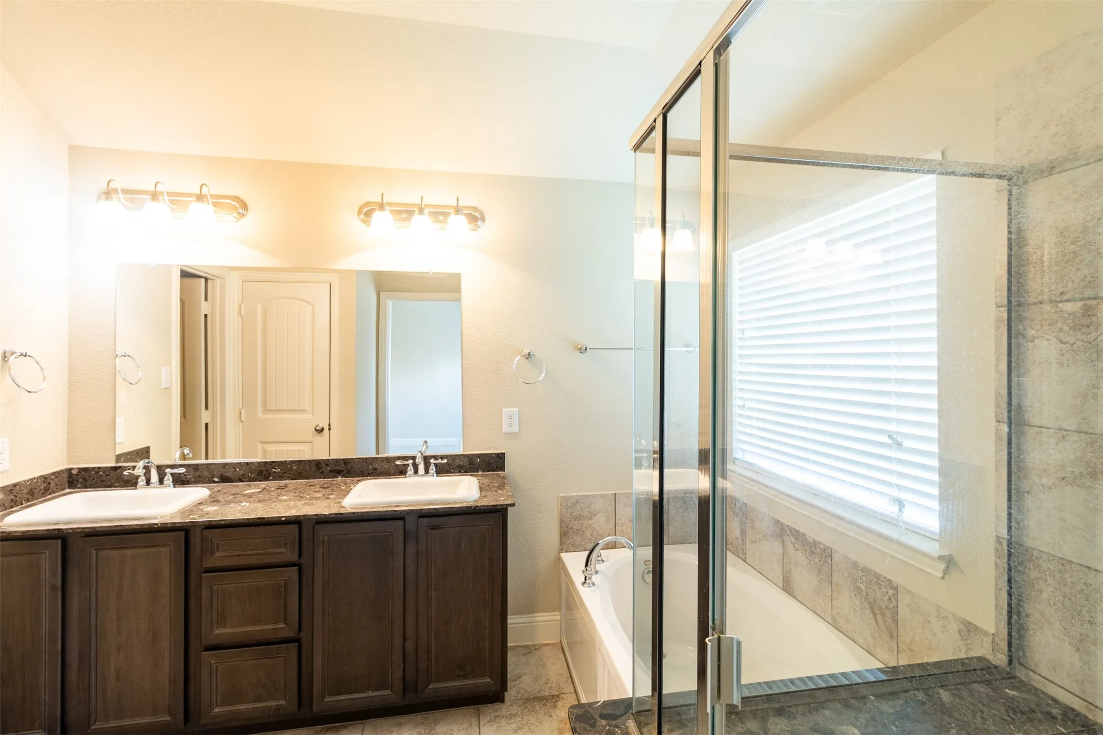 Dual vanity with dark wood-finish cabinetry, a large mirror, and individual light fixtures