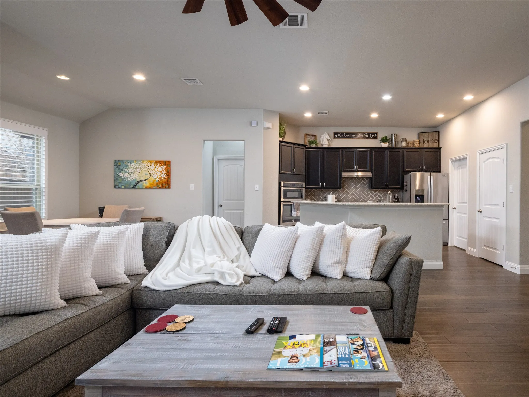 Recessed lighting, wood-finish flooring, dark cabinetry, stainless steel appliances, and a tiled kitchen backsplash
