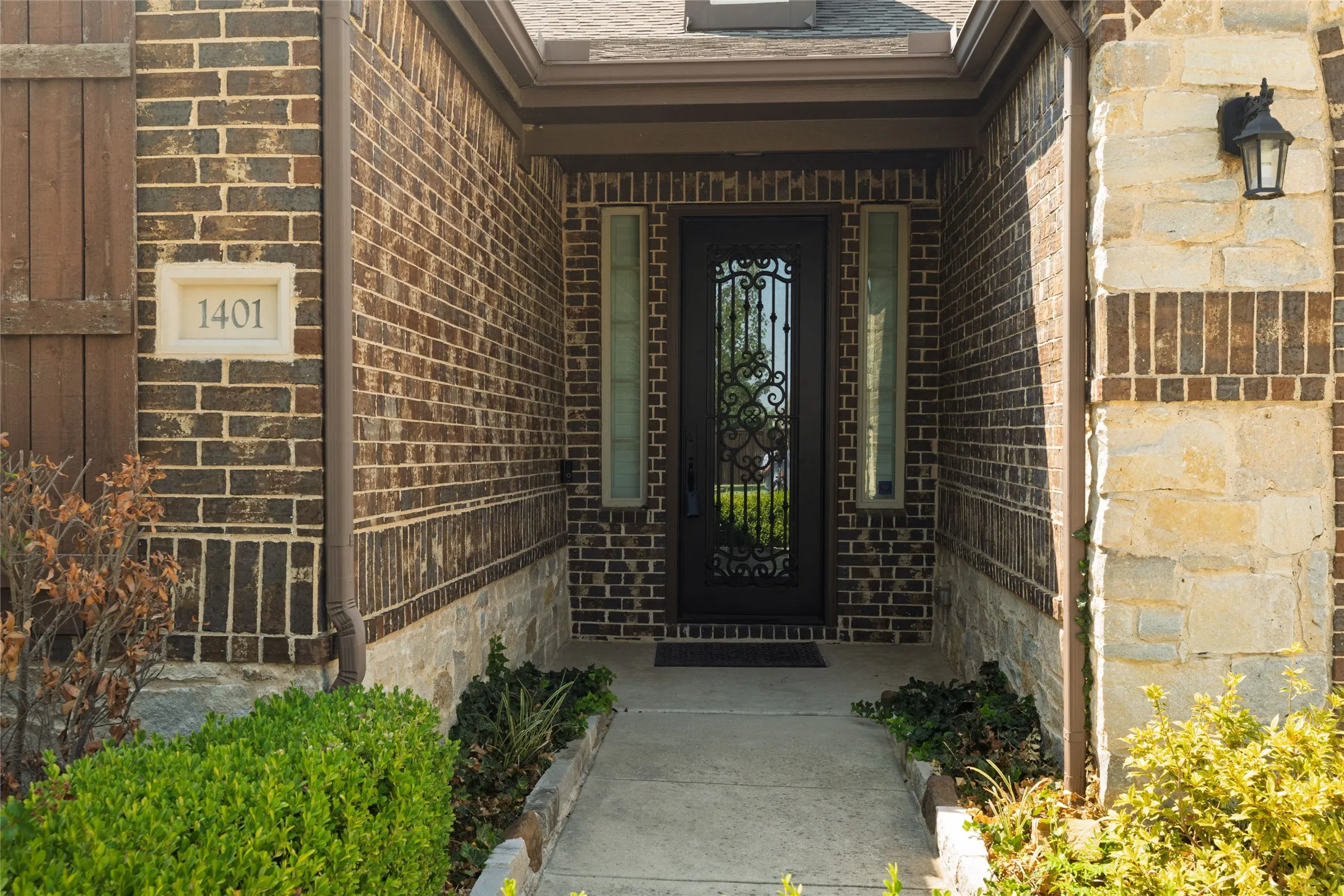 Brick exterior with stone accents and a decorative iron entry door