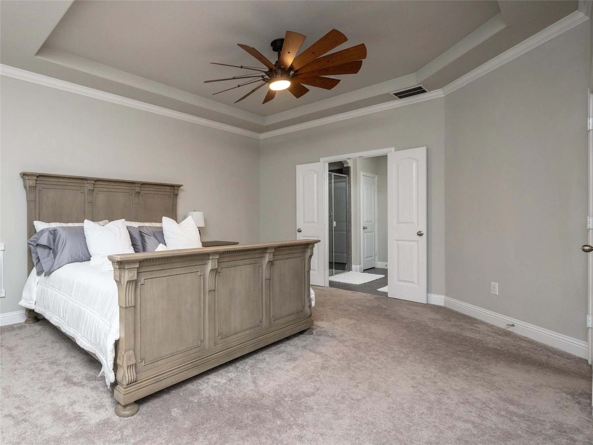 Tray ceiling with crown molding, ceiling fan, and light gray wall paint